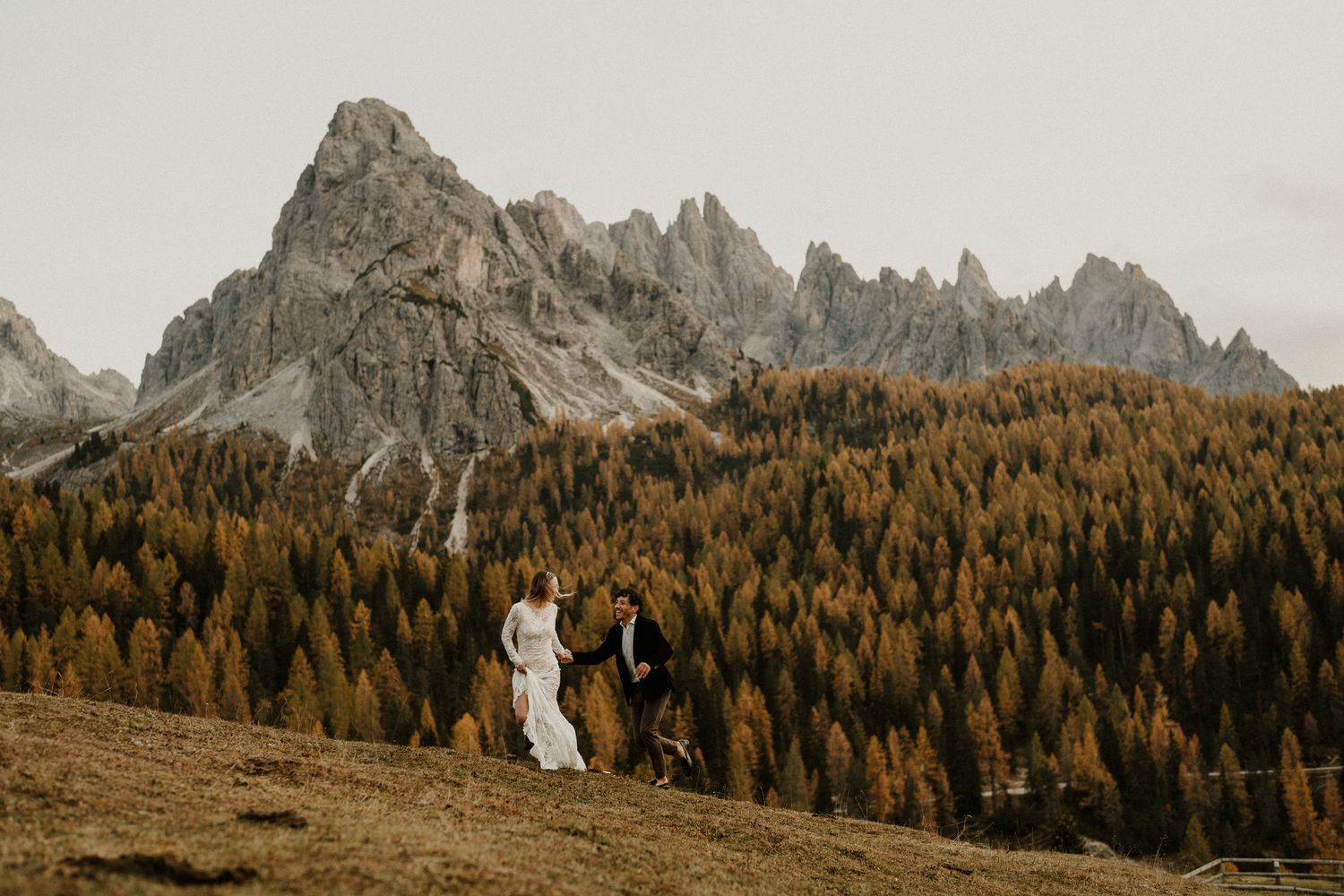 Dramatic mountain landscape with golden larches and rocky peaks in the Italian Dolomites.