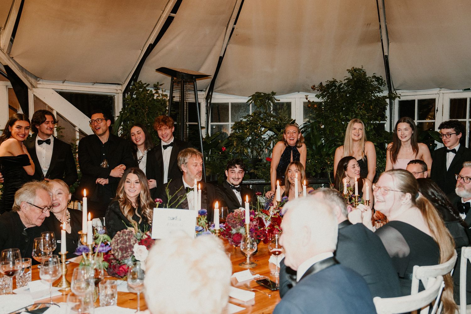 Panoramic view of wedding reception dinner with guests seated at long decorated tables.