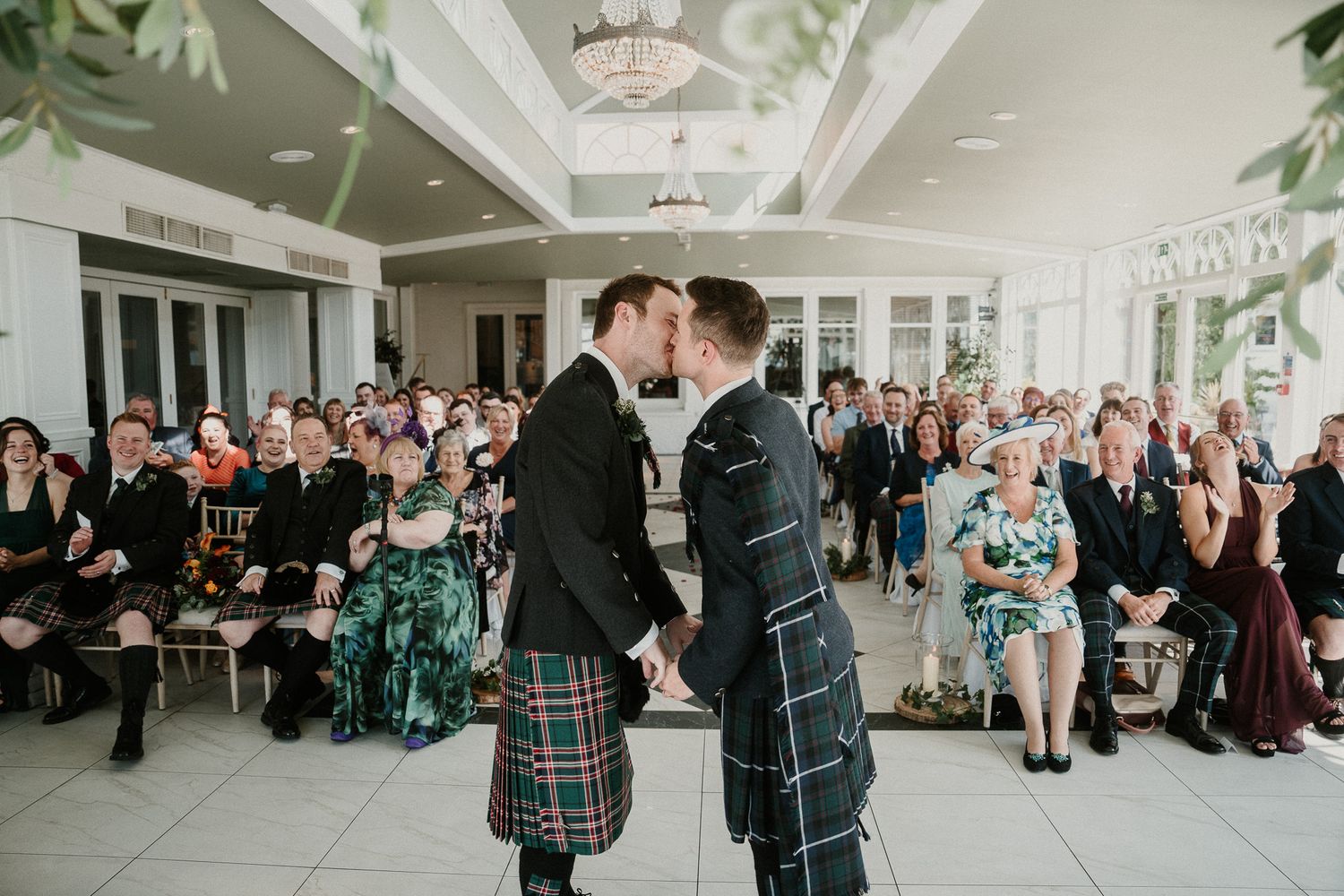 Two people in traditional Scottish kilts share a moment during their wedding ceremony.