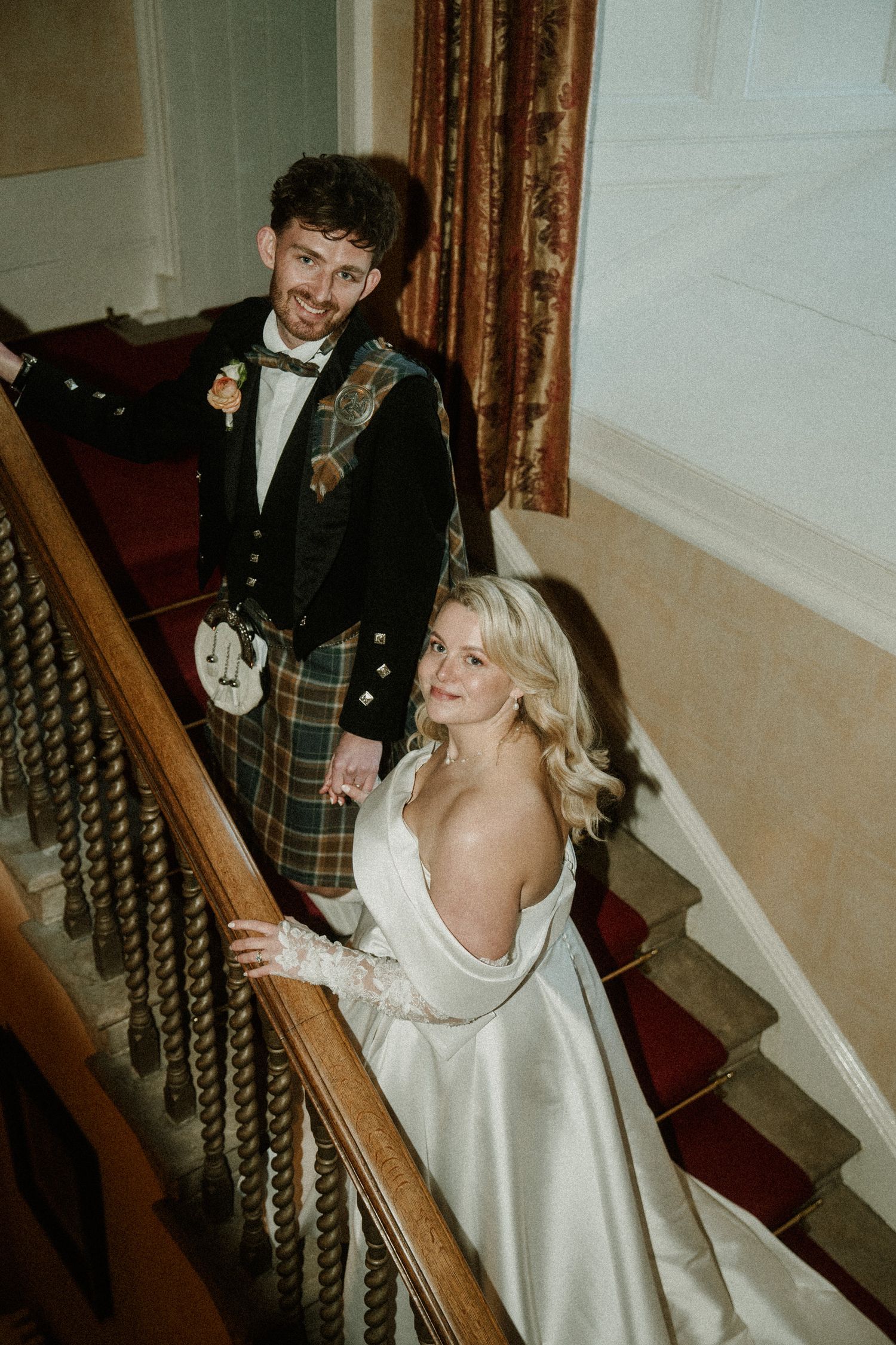 Traditional Scottish wedding attire displayed on an elegant staircase with red carpet.