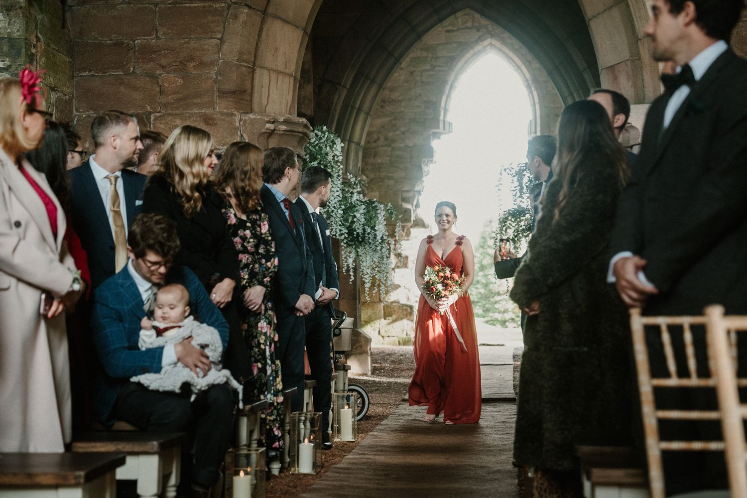 Elegant wedding ceremony takes place inside medieval stone church with arched windows.