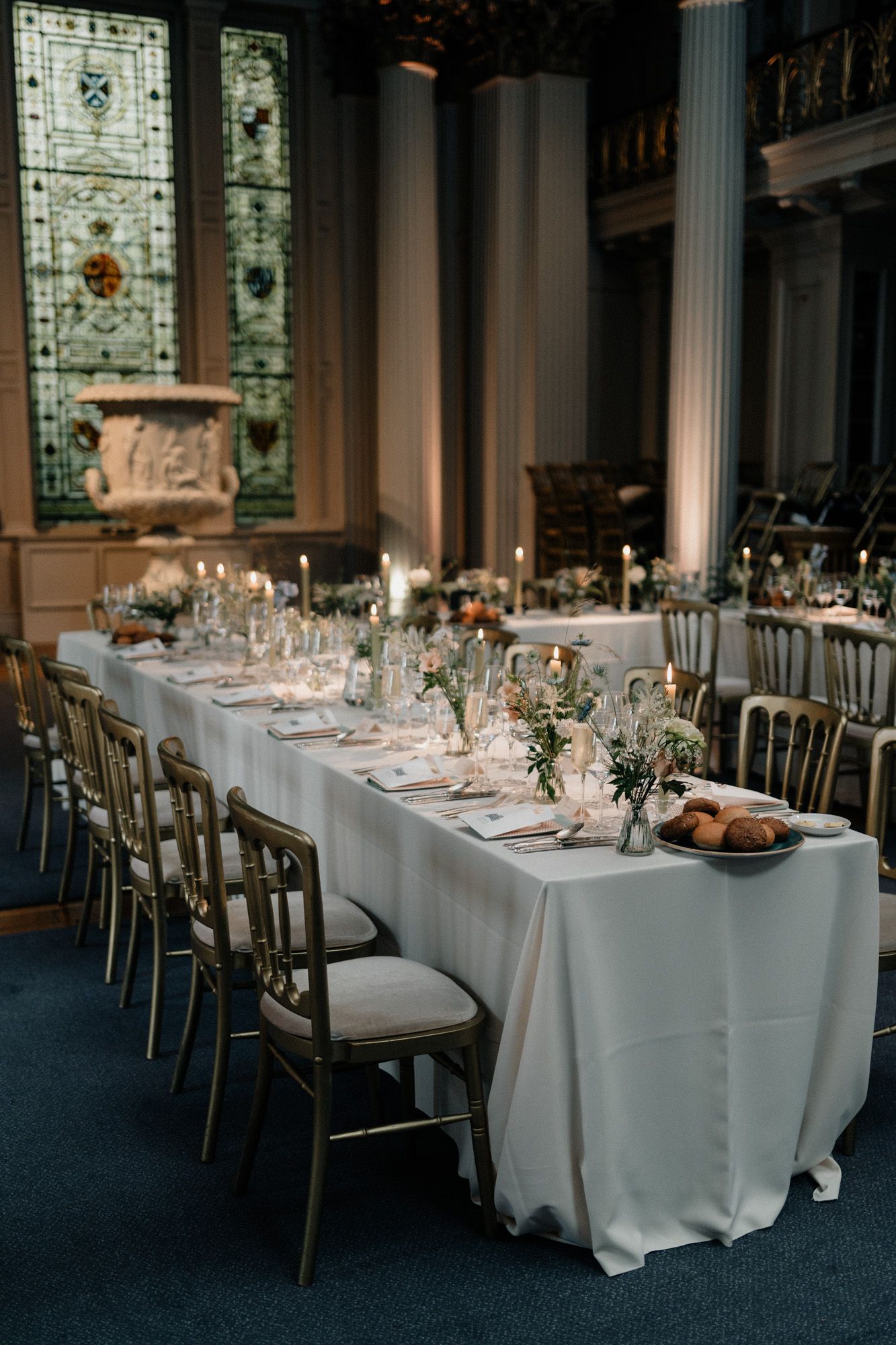 Formal dining room set for wedding reception with white linens and elegant place settings.