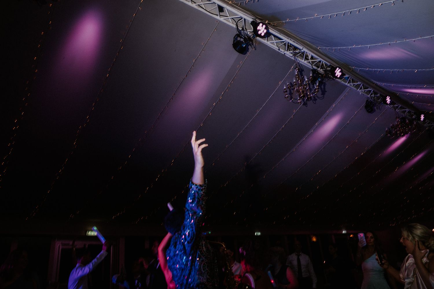 Empty dance floor with purple spotlights and ceiling draping before wedding reception.