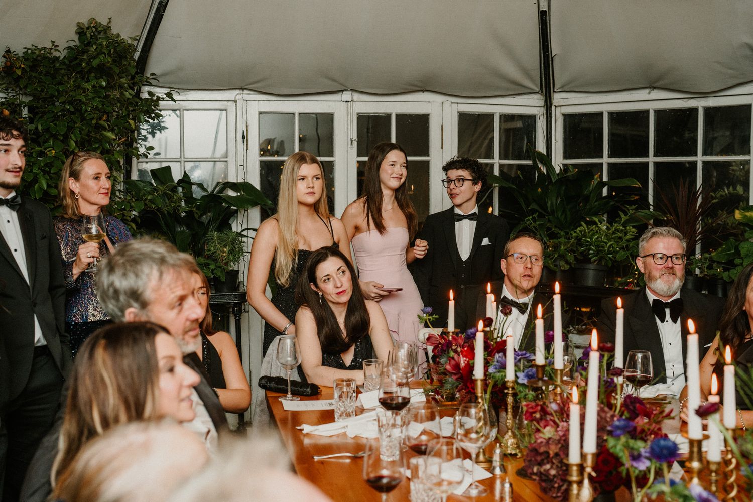 Long dining tables set for an elegant wedding reception with candles and floral arrangements.