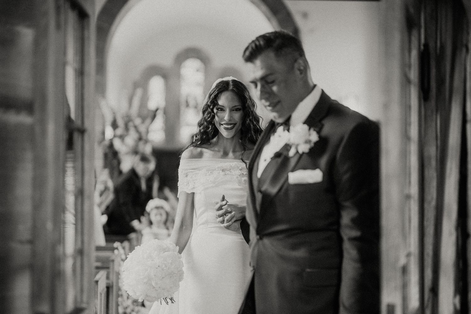 An elegant black and white wedding portrait captured in a church archway.