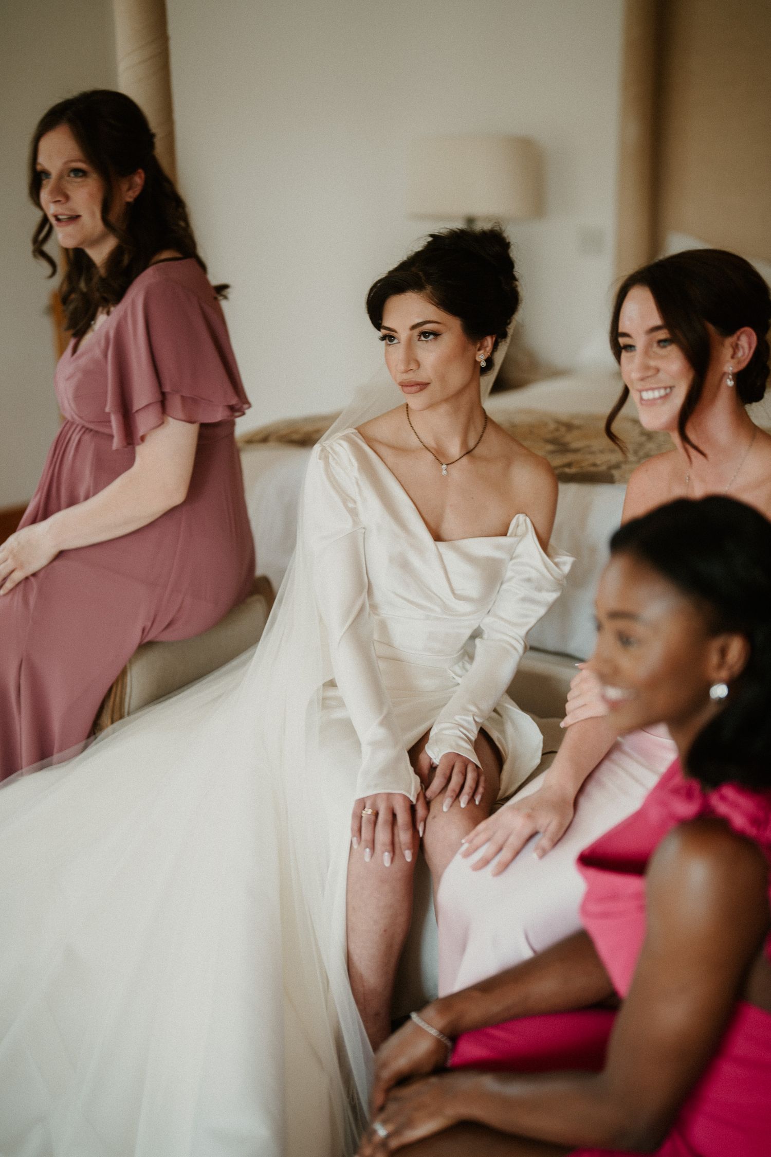 Wedding party in pink and white dresses sitting together before the ceremony.