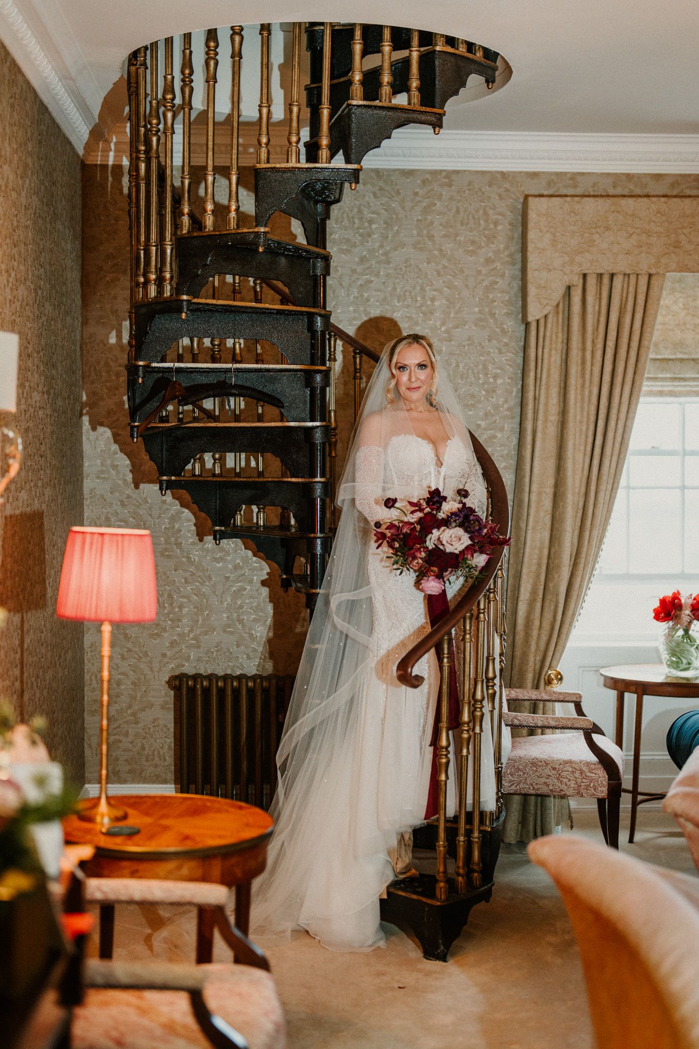Elegant spiral staircase in a vintage-style room with warm lighting and wedding decor.