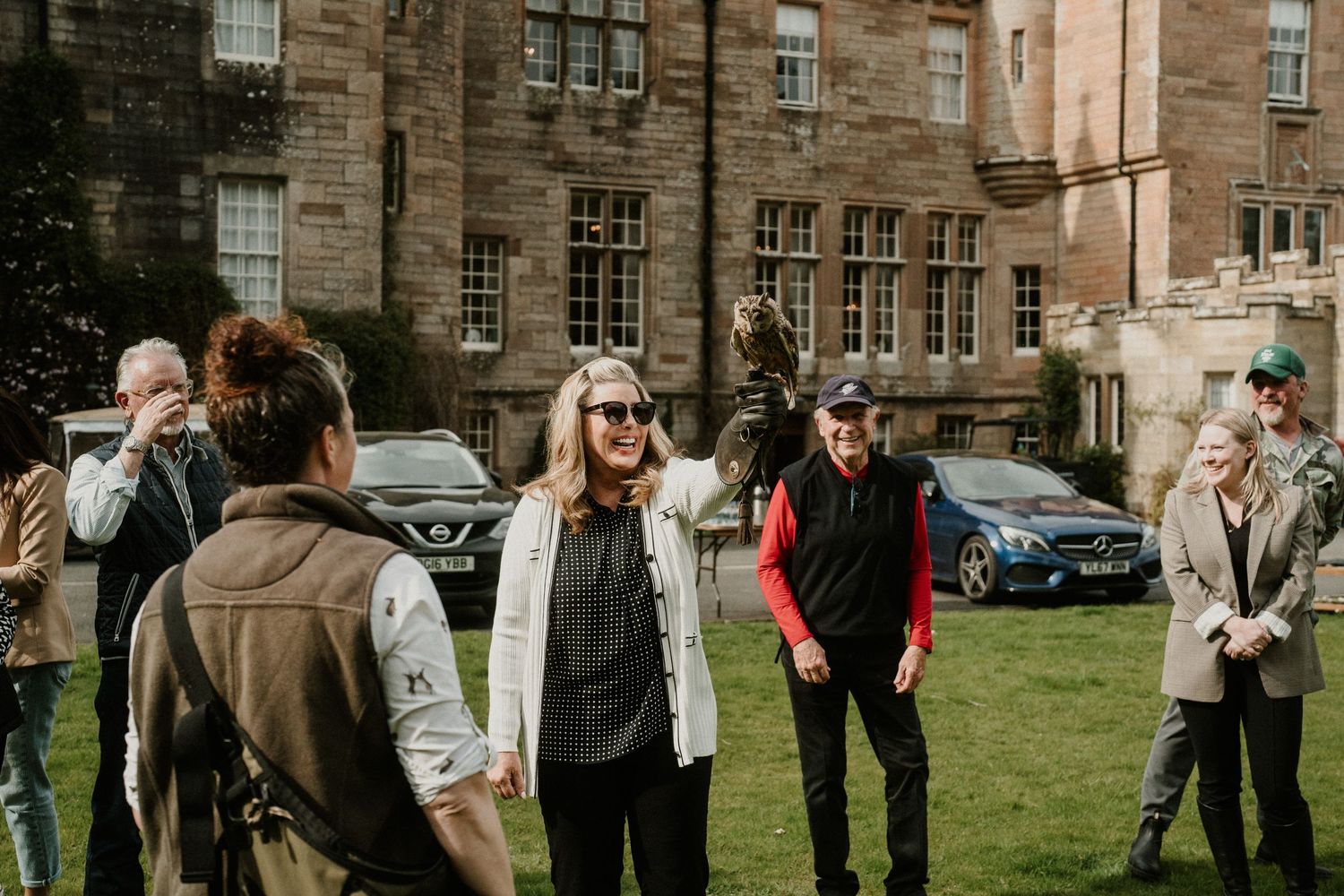 A group gathers on a lawn outside a historic stone building during an outdoor event.