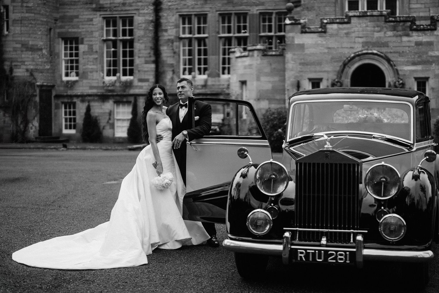Vintage Rolls Royce and classic cars lined up at elegant stone venue.