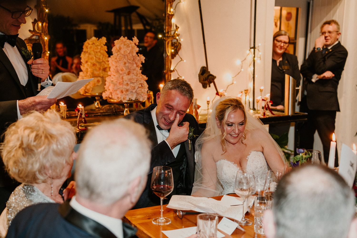 Elegant wedding reception dinner with ornate chandeliers and candlelit table settings.