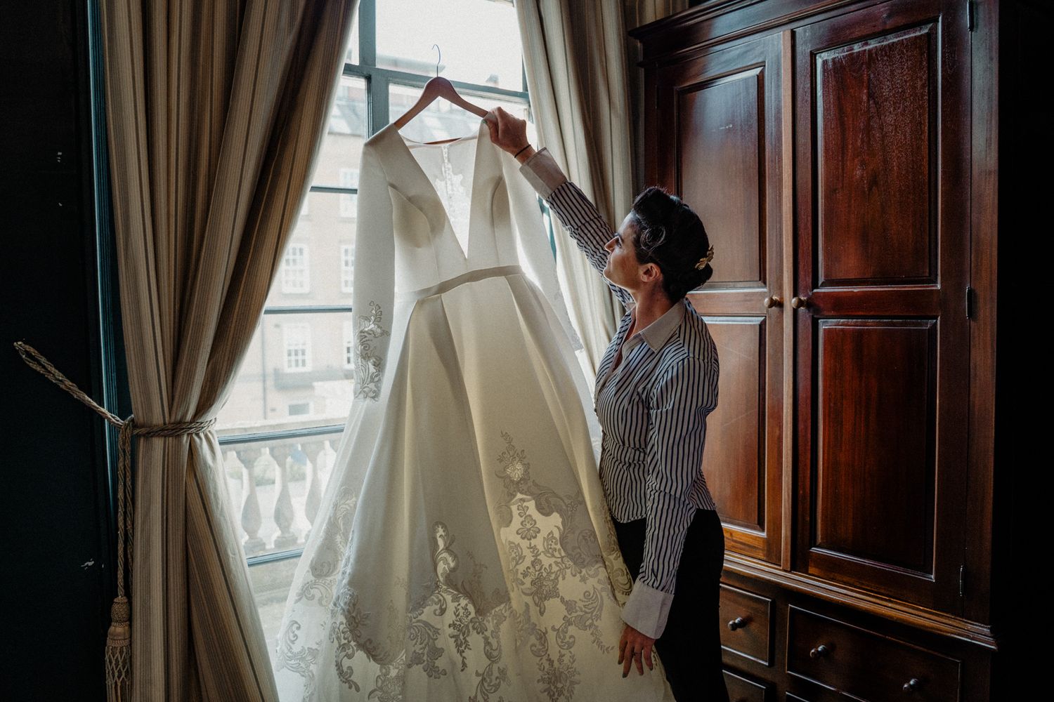 Elegant curtains frame a window in a warmly lit room with wood paneling and classic decor.