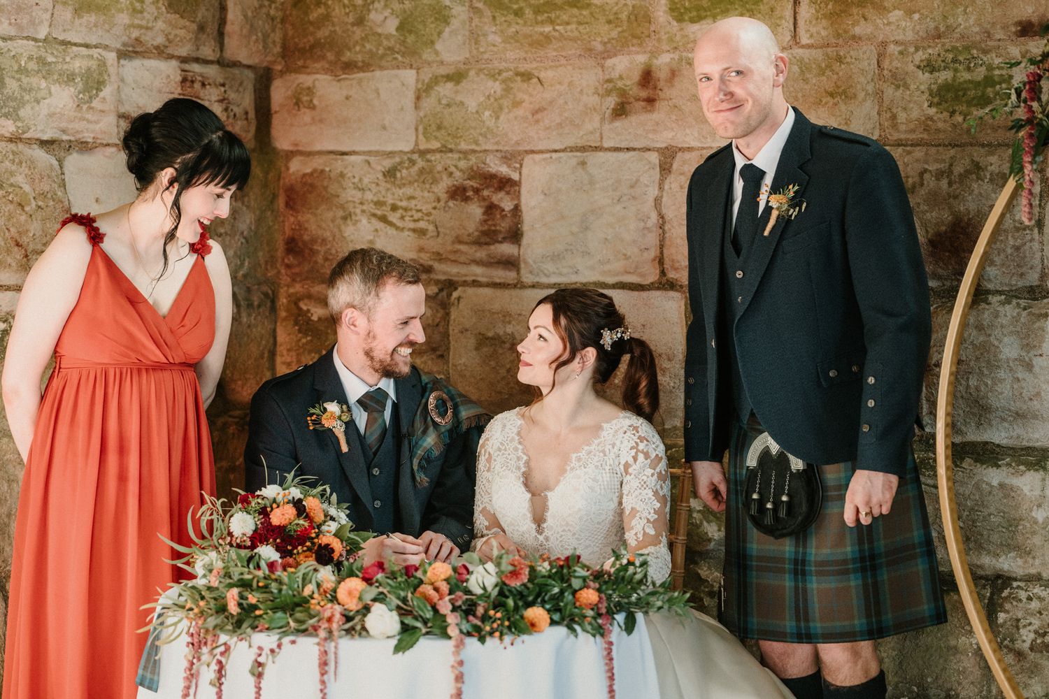 Scottish wedding celebration with traditional kilts and vibrant floral arrangements on the table.