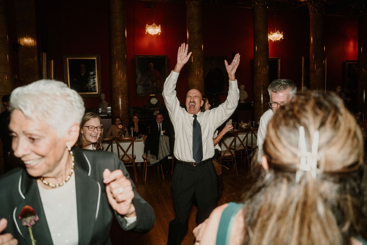 Wedding reception dance party with guests celebrating in an elegant indoor venue.