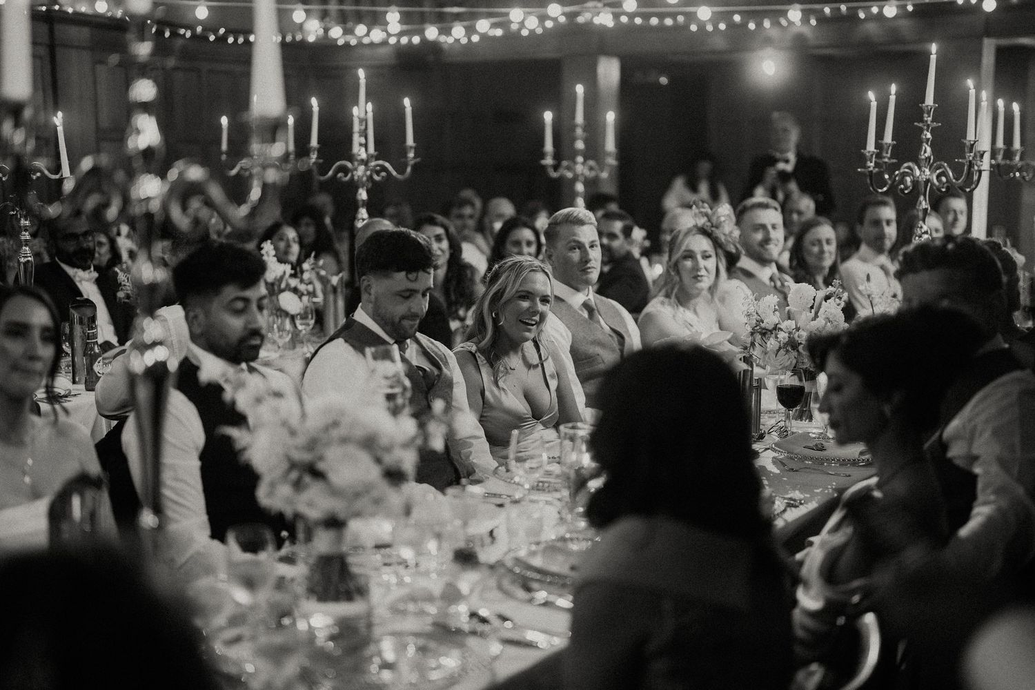 Wedding guests seated at long tables during an evening reception celebration.