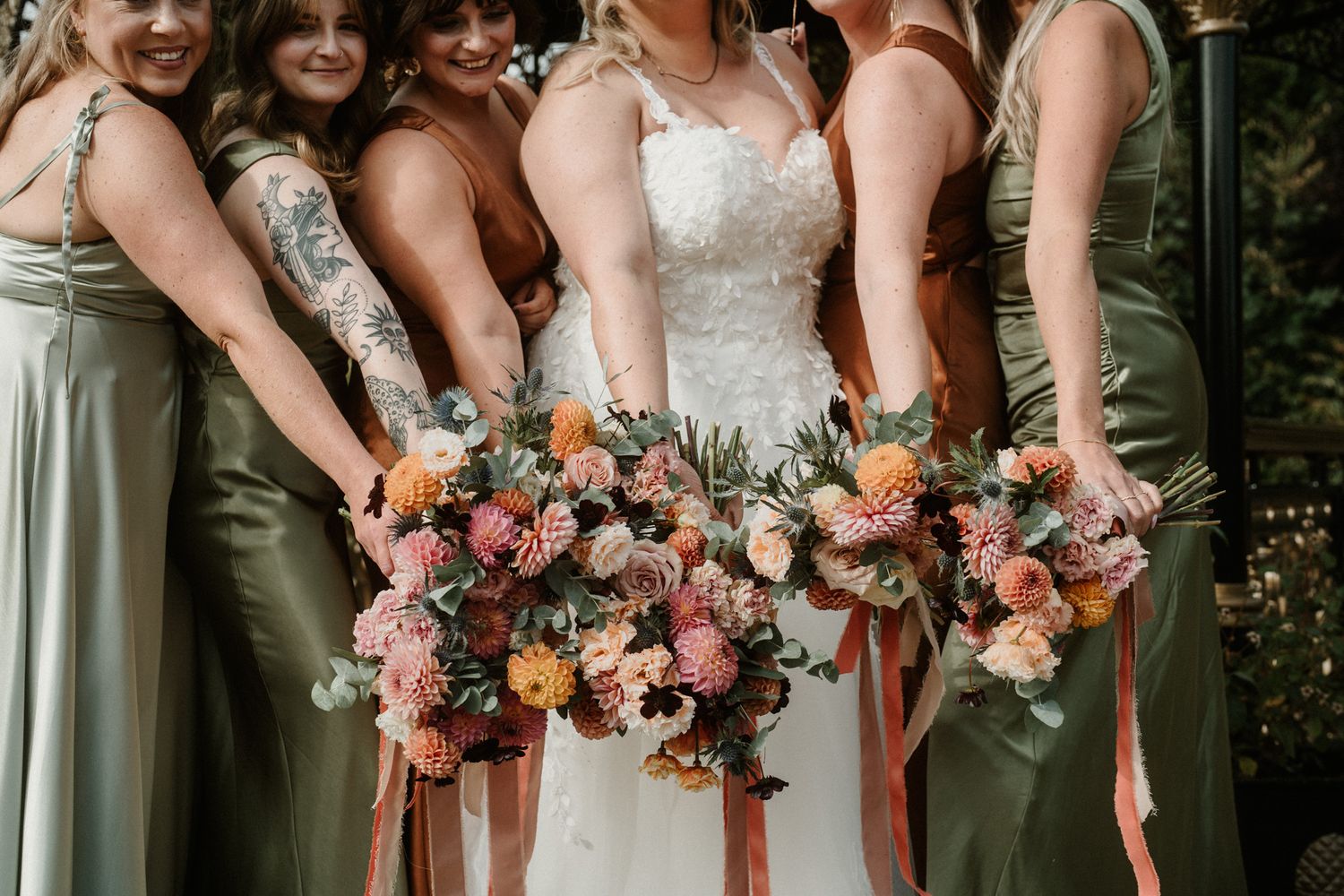 Close-up of bridesmaids holding colorful peach and pink wedding bouquets.