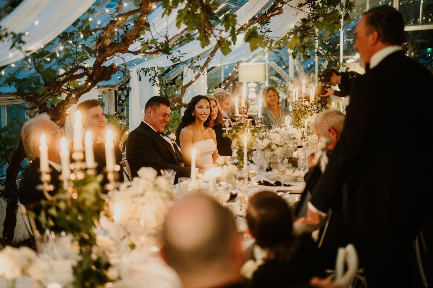 Candlelit wedding reception dinner under a tent with glowing ambiance.