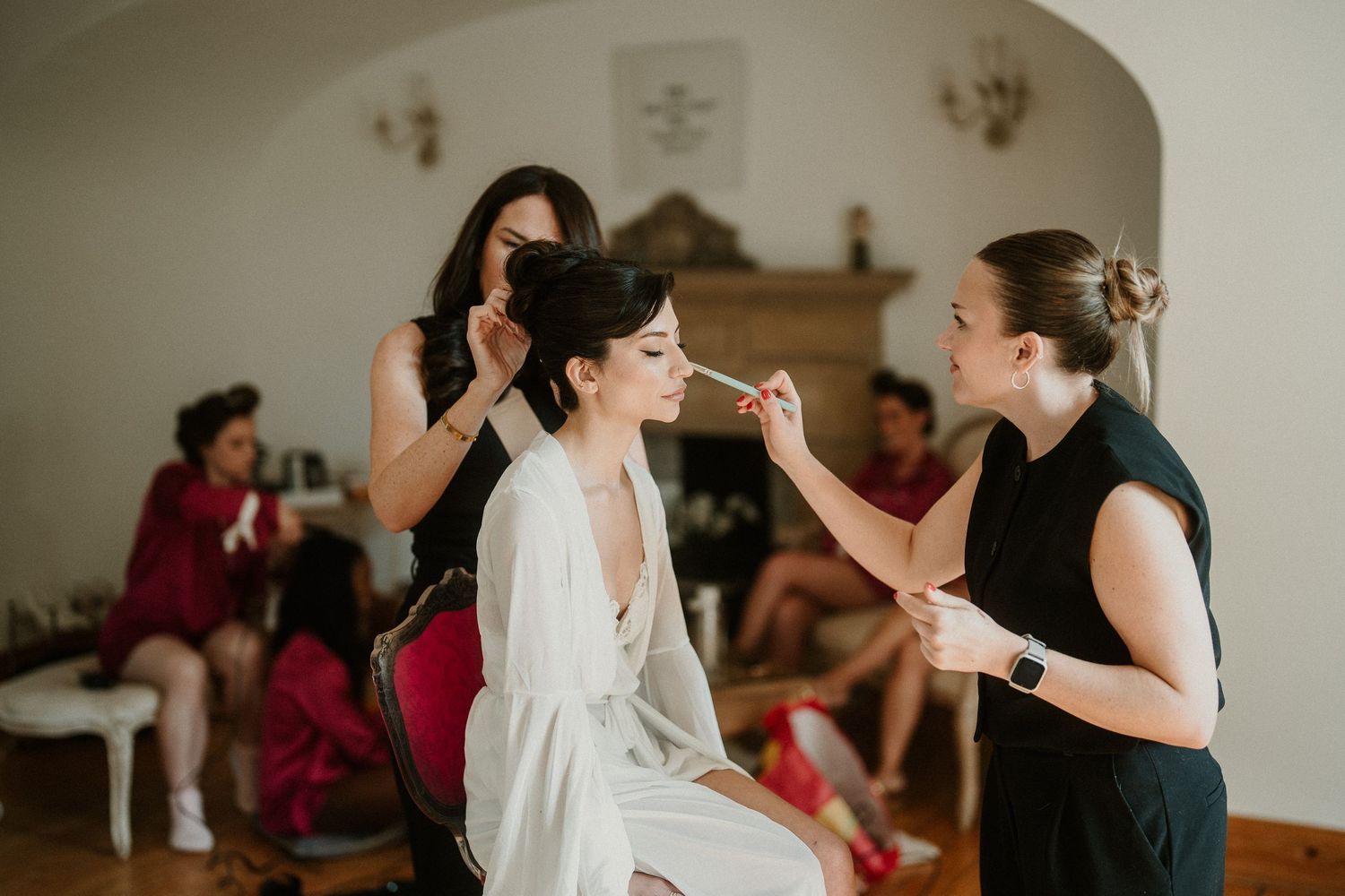 Wedding preparation scene showing makeup application in an elegant room.
