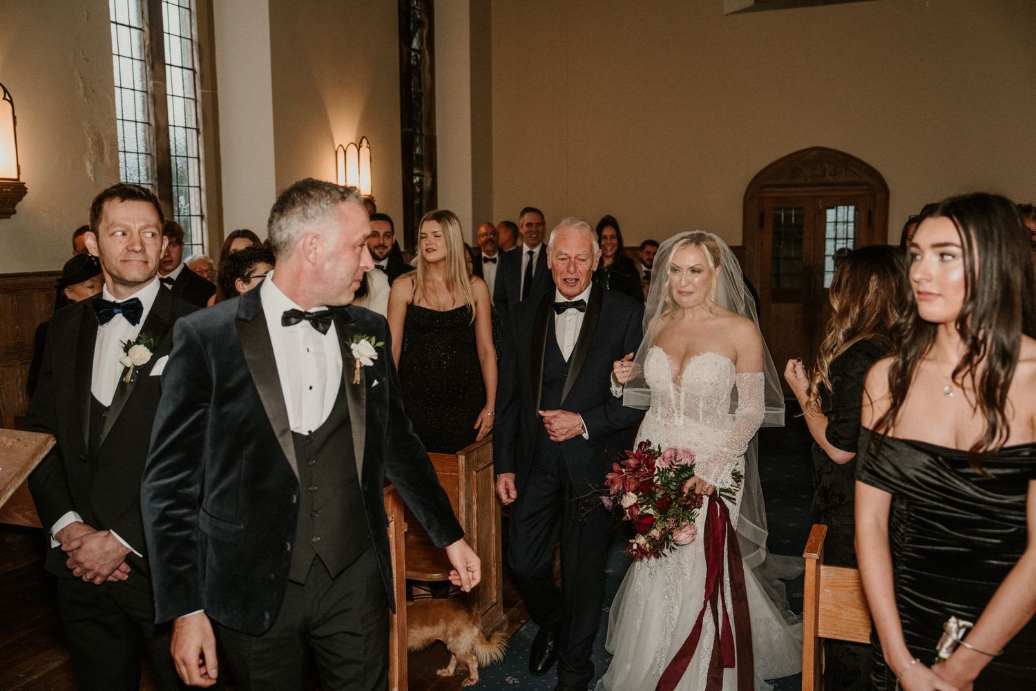 Wedding guests gather in a church interior with warm lighting and elegant decor.
