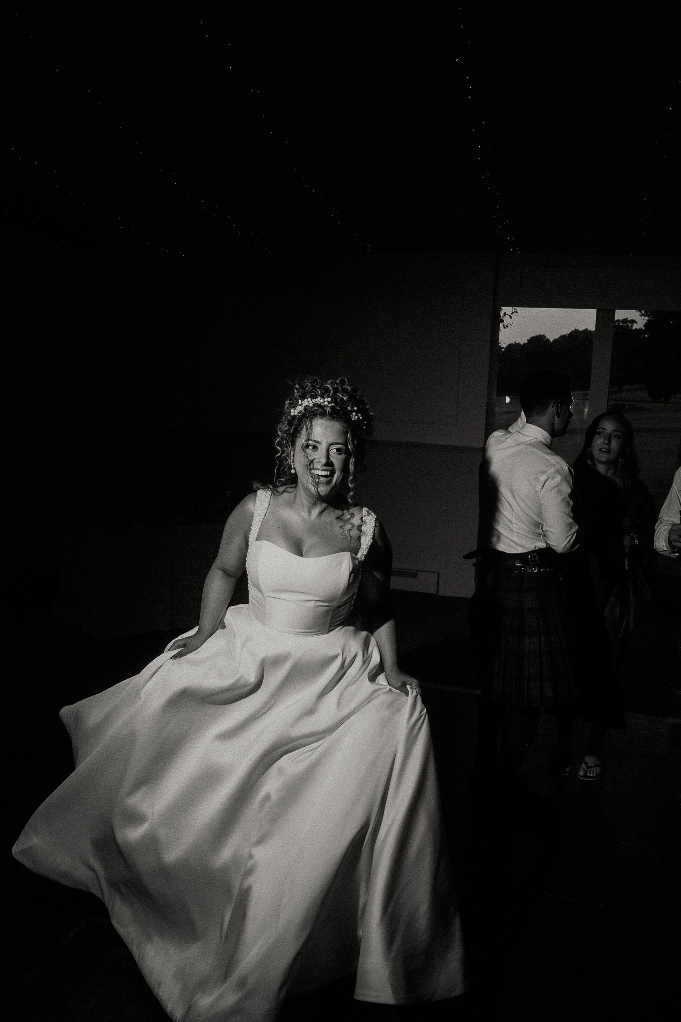 Dramatic black and white photo of a bride in an elegant white gown during the reception.
