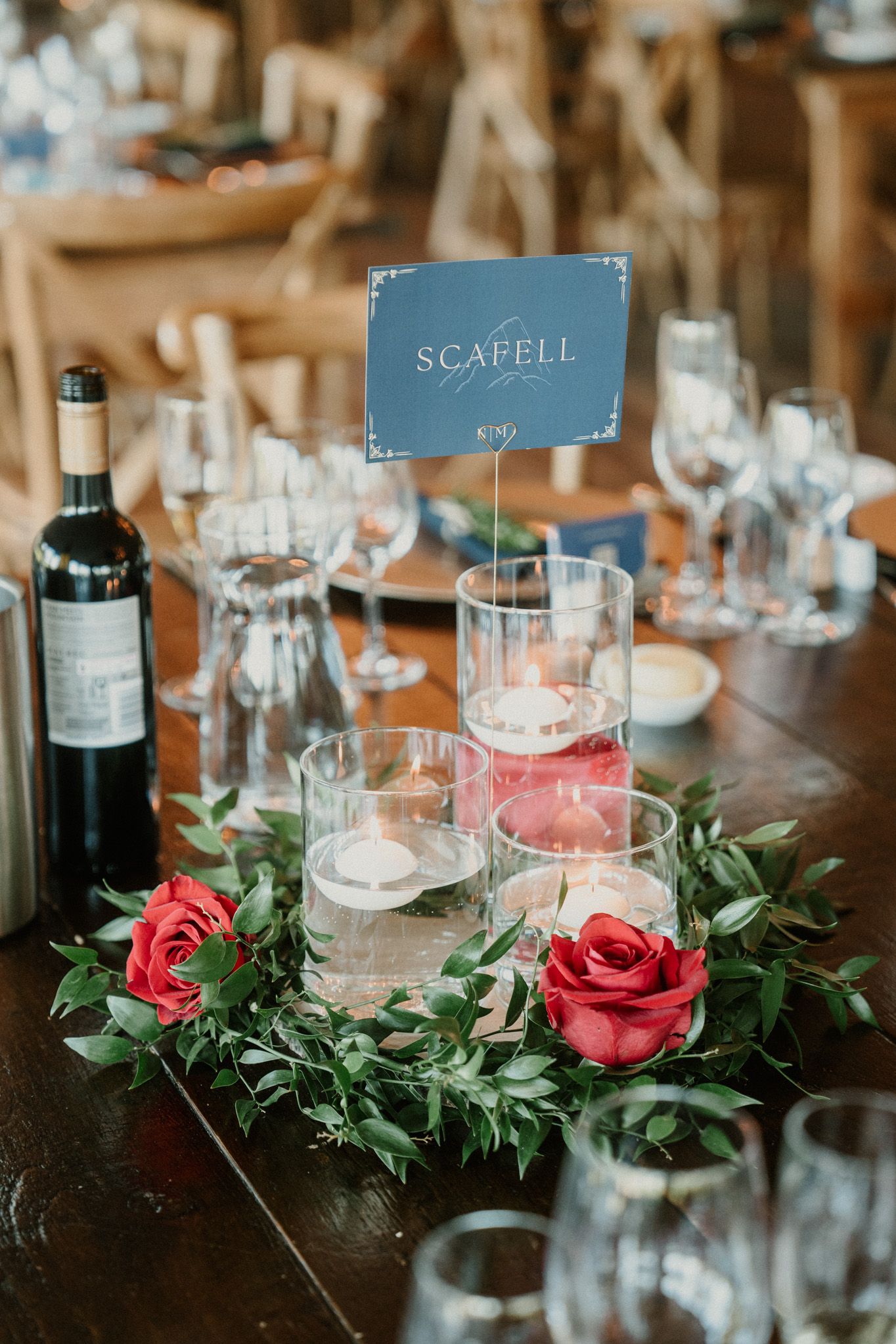 Wedding reception table setting with Scafell sign, red roses and wine glasses.