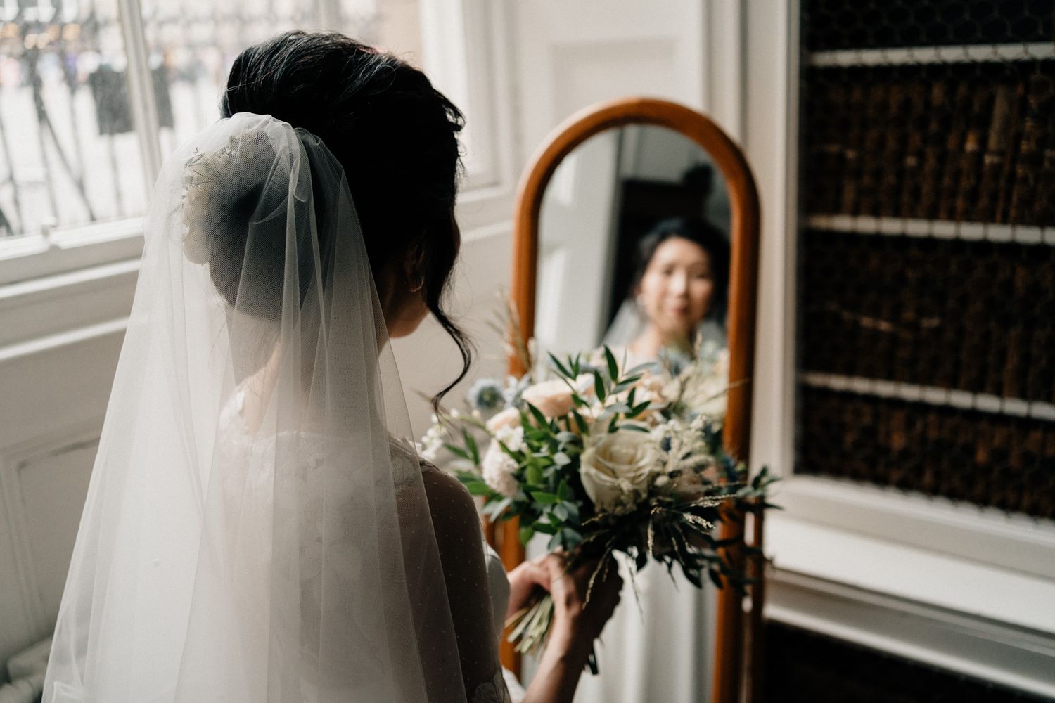 Elegant bridal details including white veil and floral arrangements in a sunlit room.