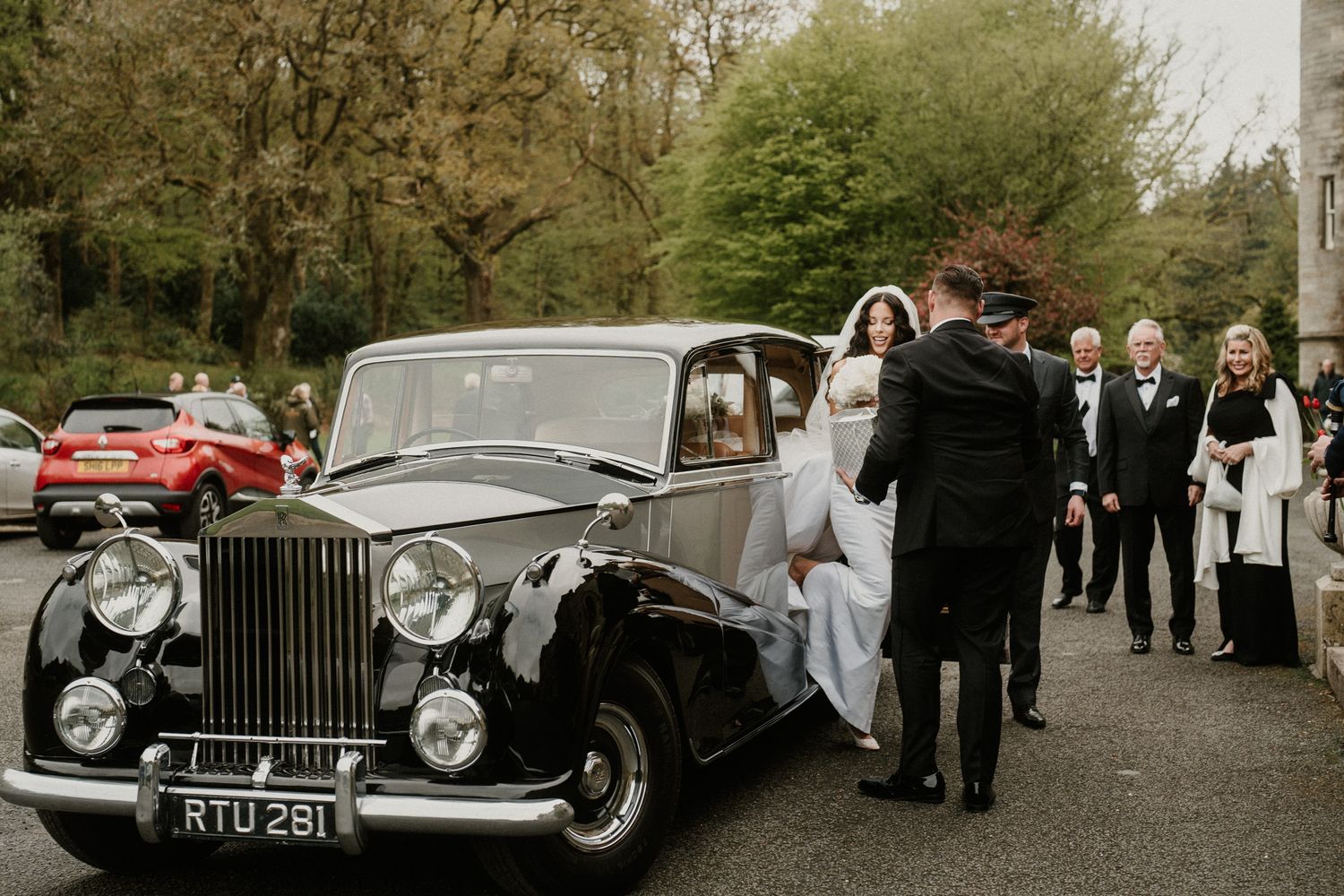Collection of vintage luxury cars lined up outside historic wedding venue.