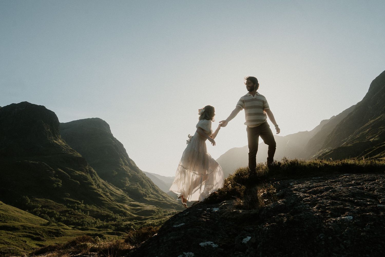 Couple exploring scenic mountain trail during sunset photoshoot.