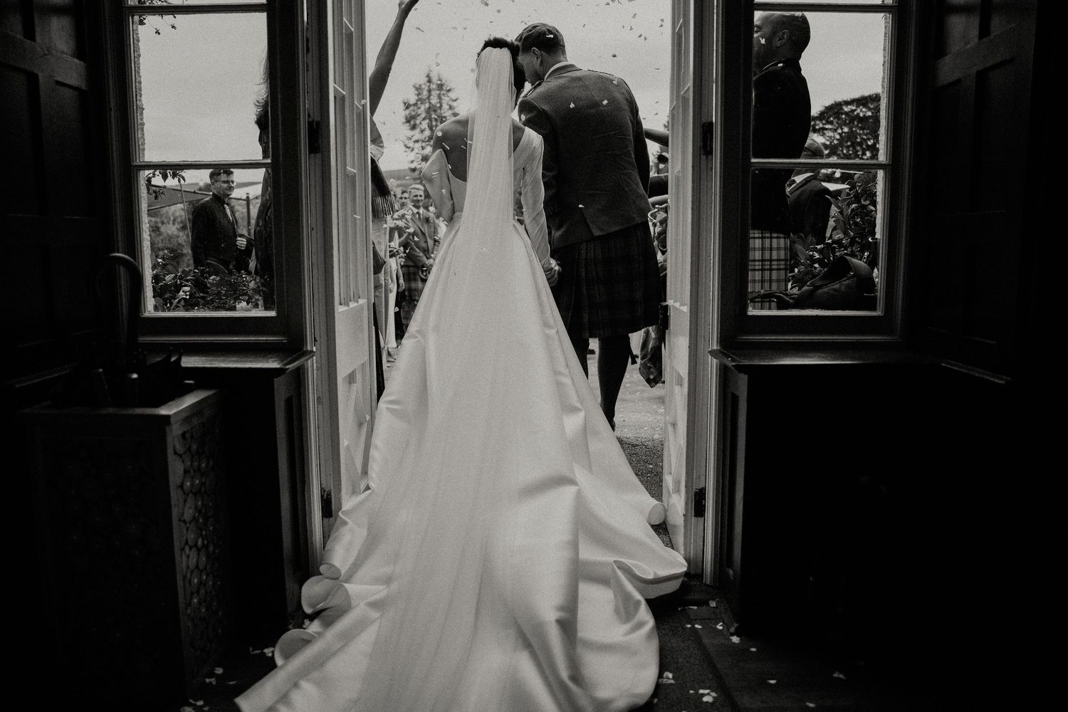 Black and white wedding photography capturing dramatic moments through doorway frames.