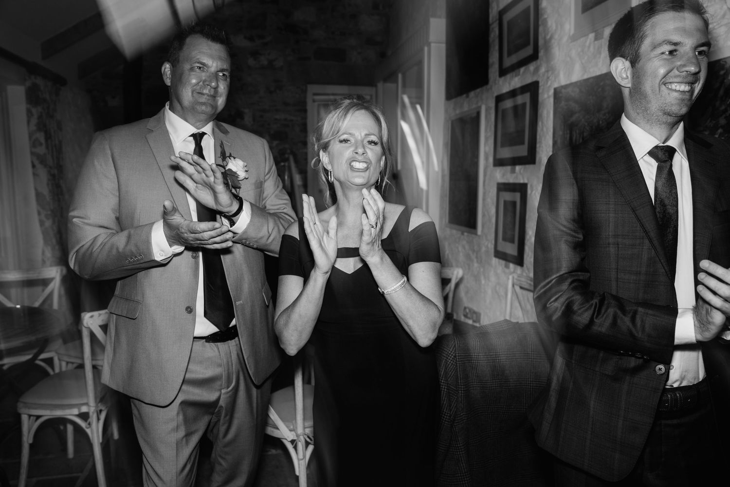 Three people sharing a joyful moment at an indoor gathering with drinks in their hands.