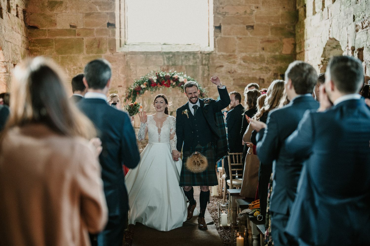 Wedding celebration inside a rustic stone venue with guests seated in rows.