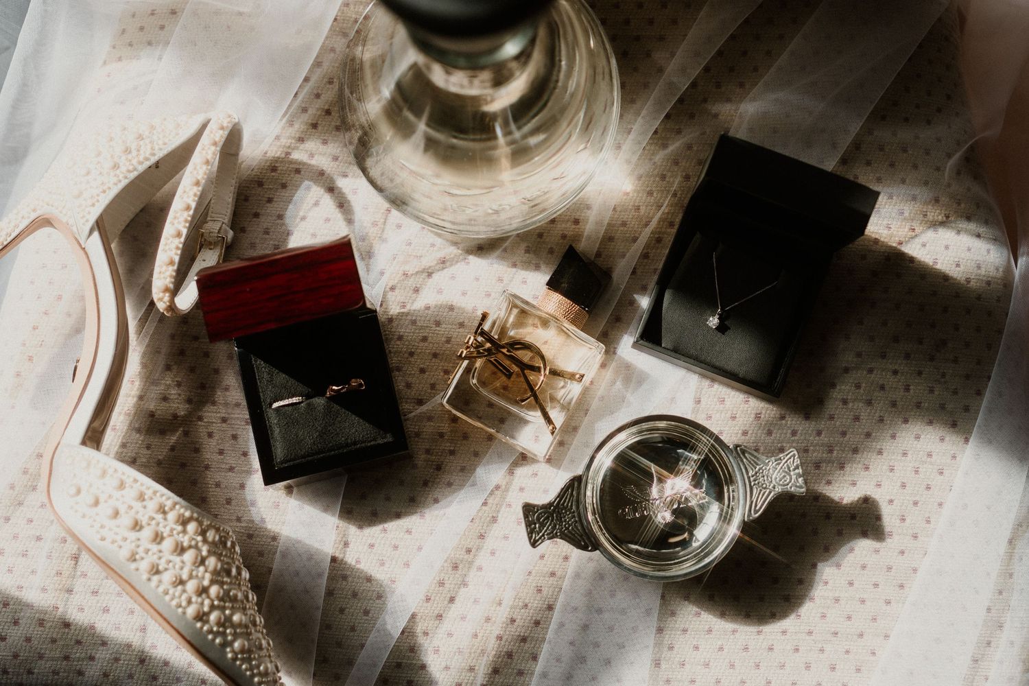 Wedding accessories including shoes and jewelry arranged on a light surface.