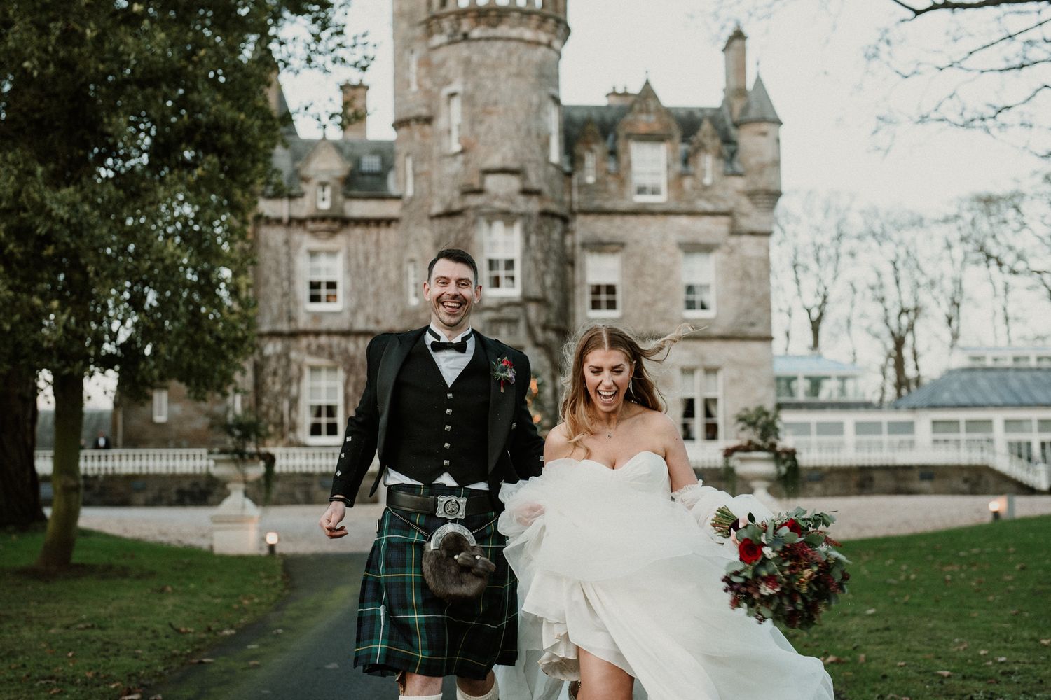 Scottish castle wedding portrait with couple on lawn.