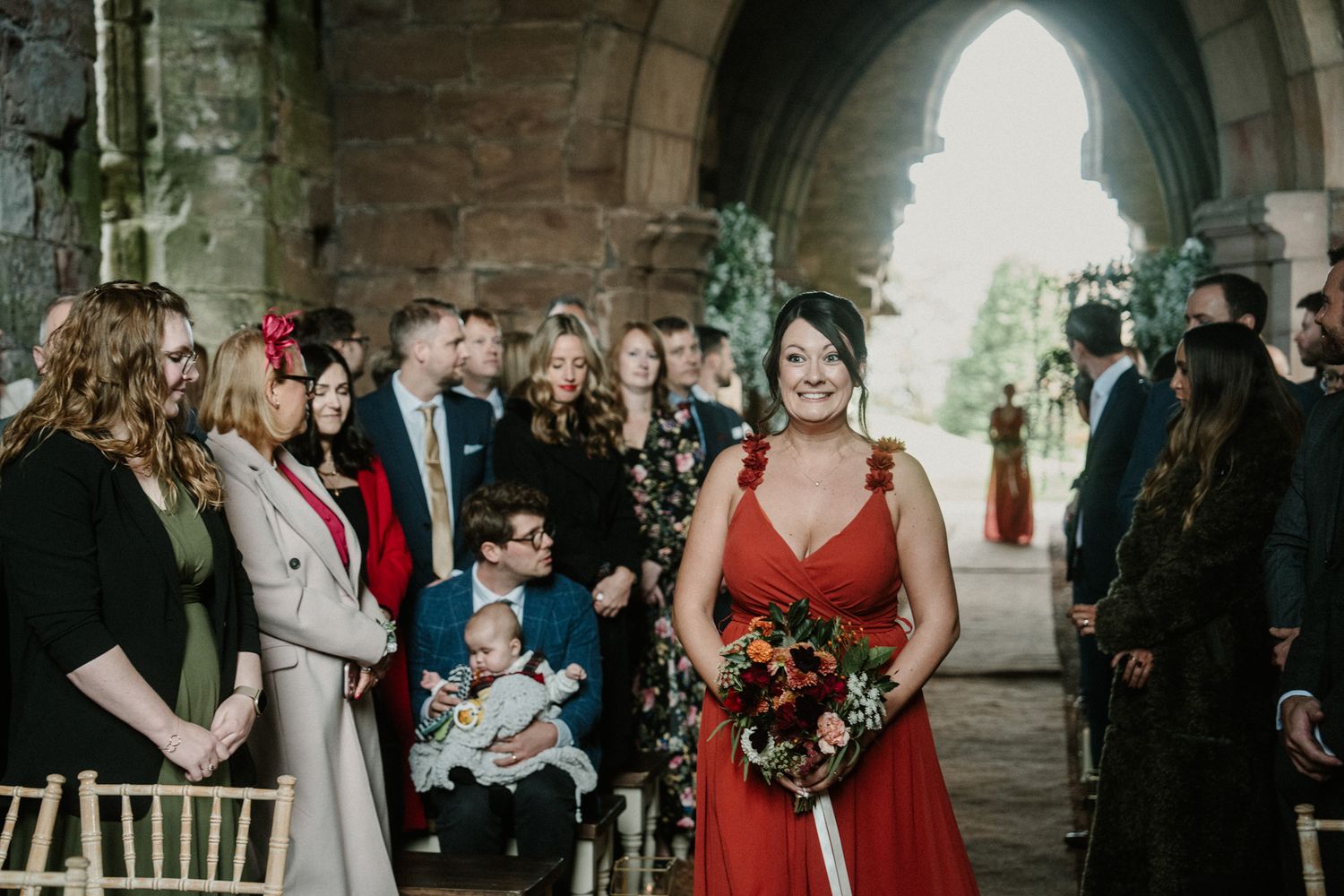 Wedding party stands in atmospheric stone church interior with dramatic lighting.