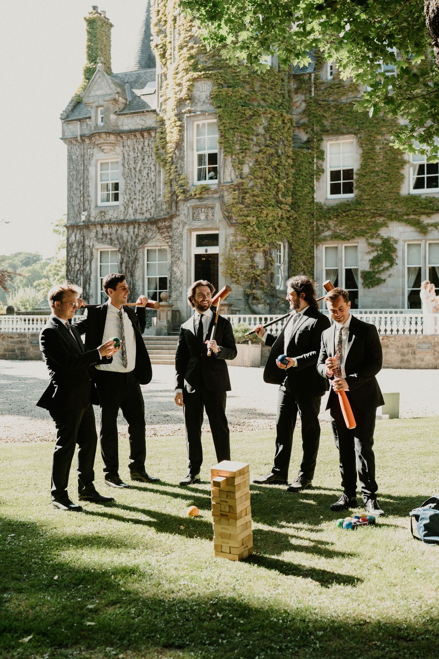 Groomsmen playing outdoor games and having fun on the castle lawn before the wedding ceremony.