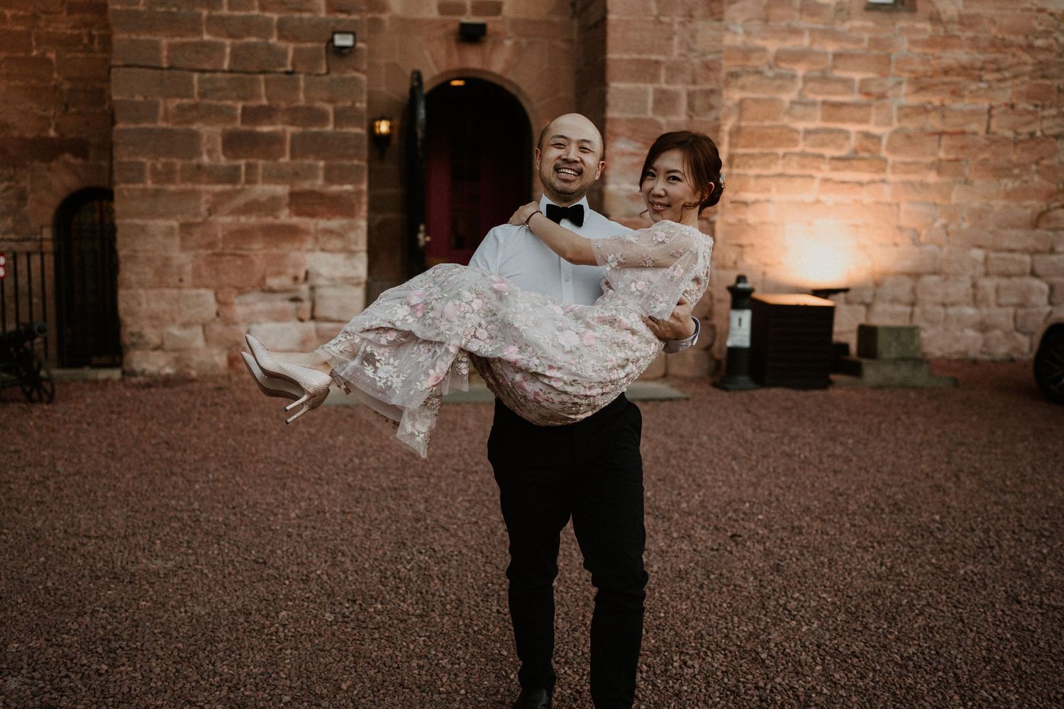 A couple dances in front of exposed brick walls in an indoor venue.