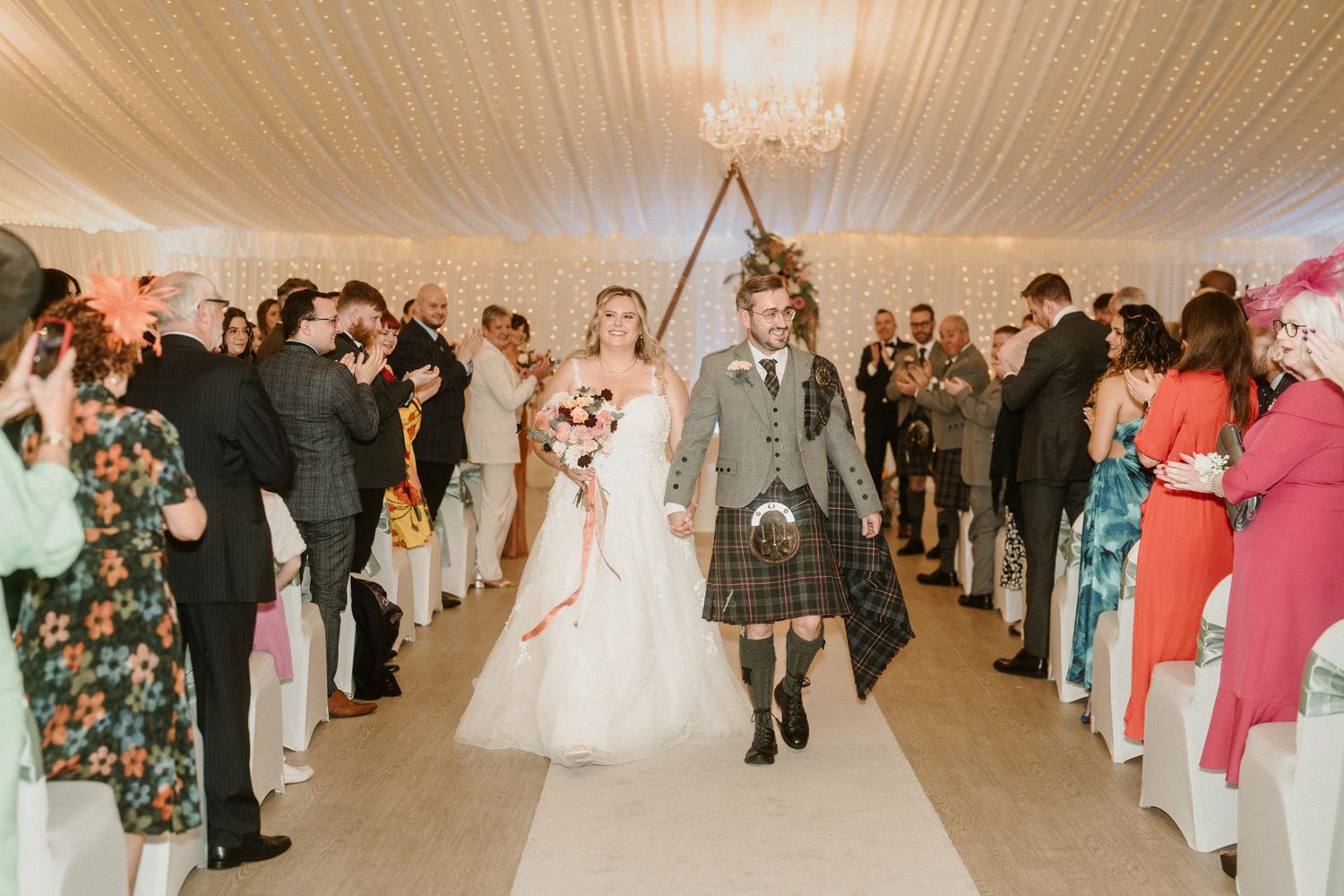 Wedding reception hall with white draping and guests enjoying the celebration.