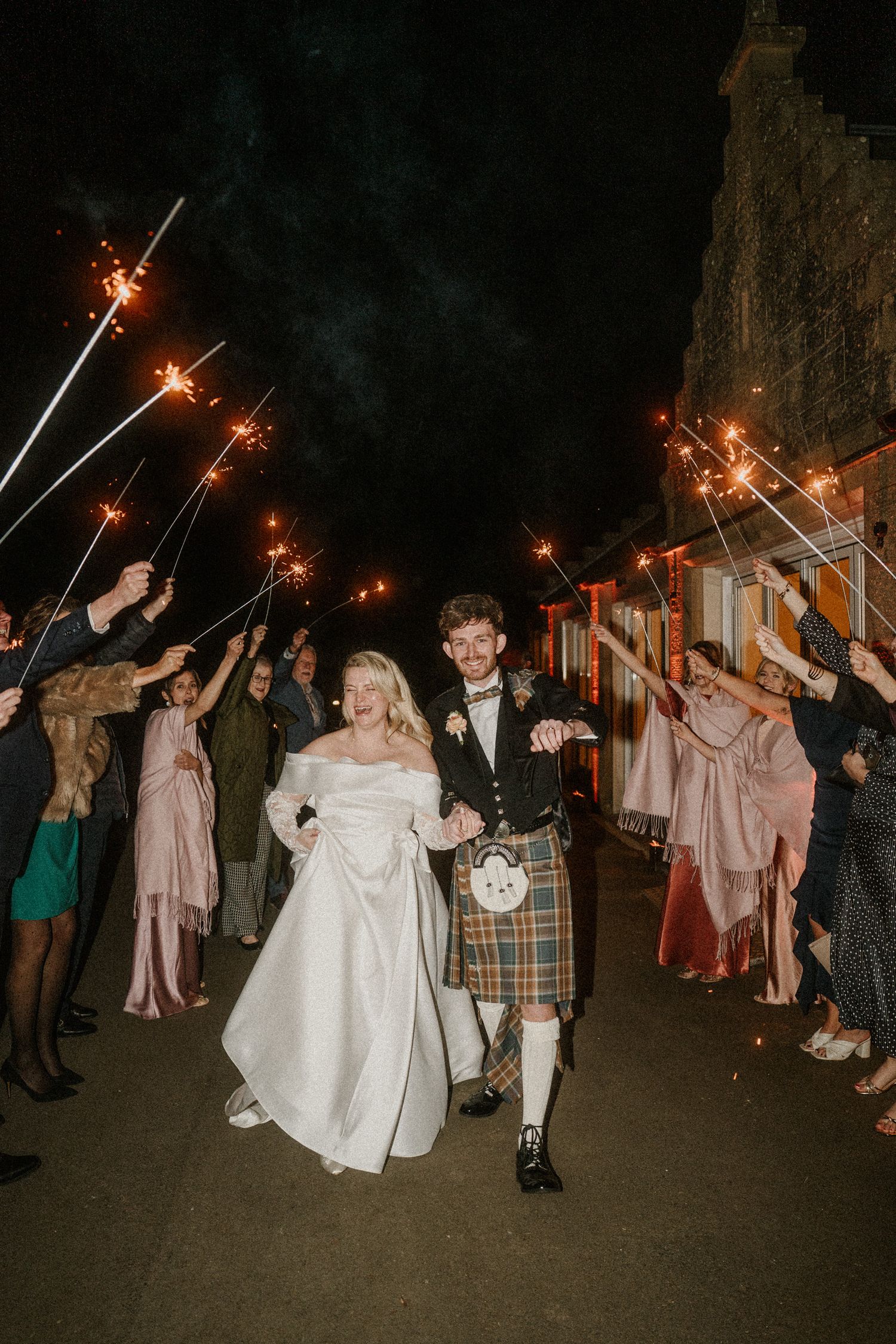 Wedding exit celebration with sparklers lighting up the night as guests line the pathway.