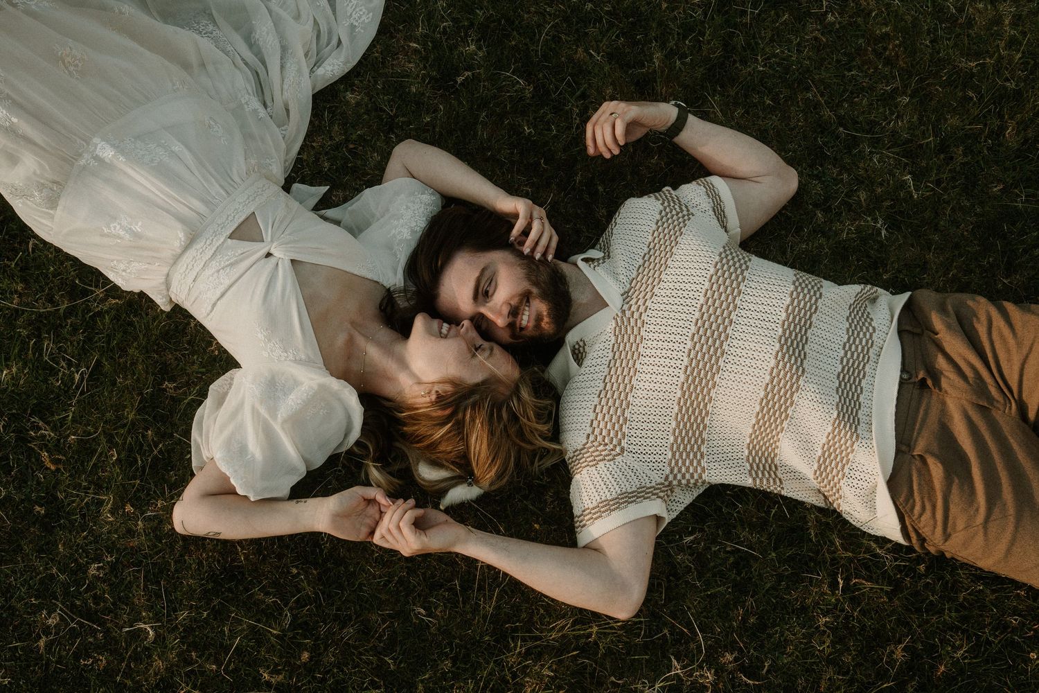 Couple lying together on grass during an intimate outdoor photo session.