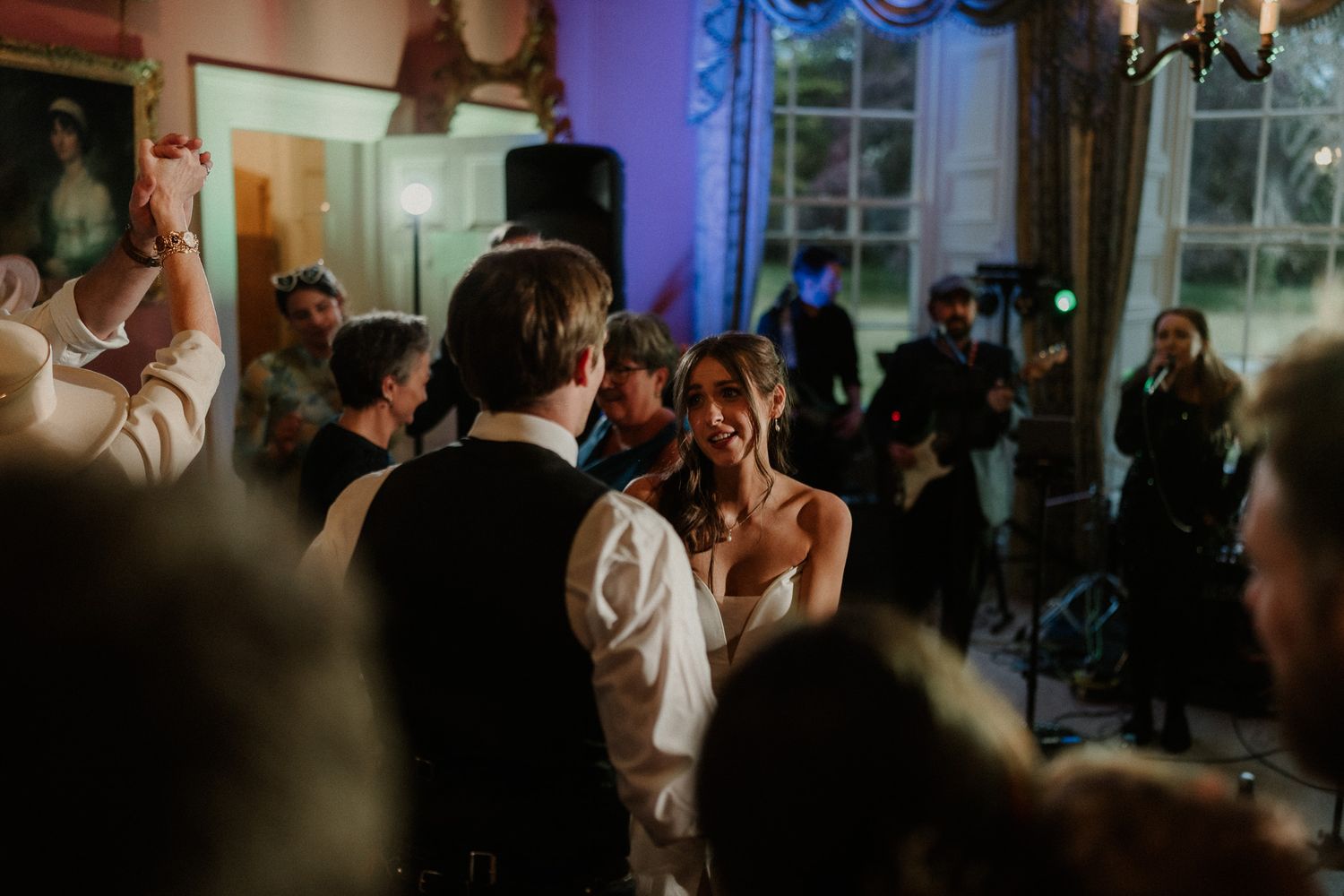 Bride and groom share a joyful dance surrounded by guests at an elegant evening wedding reception.