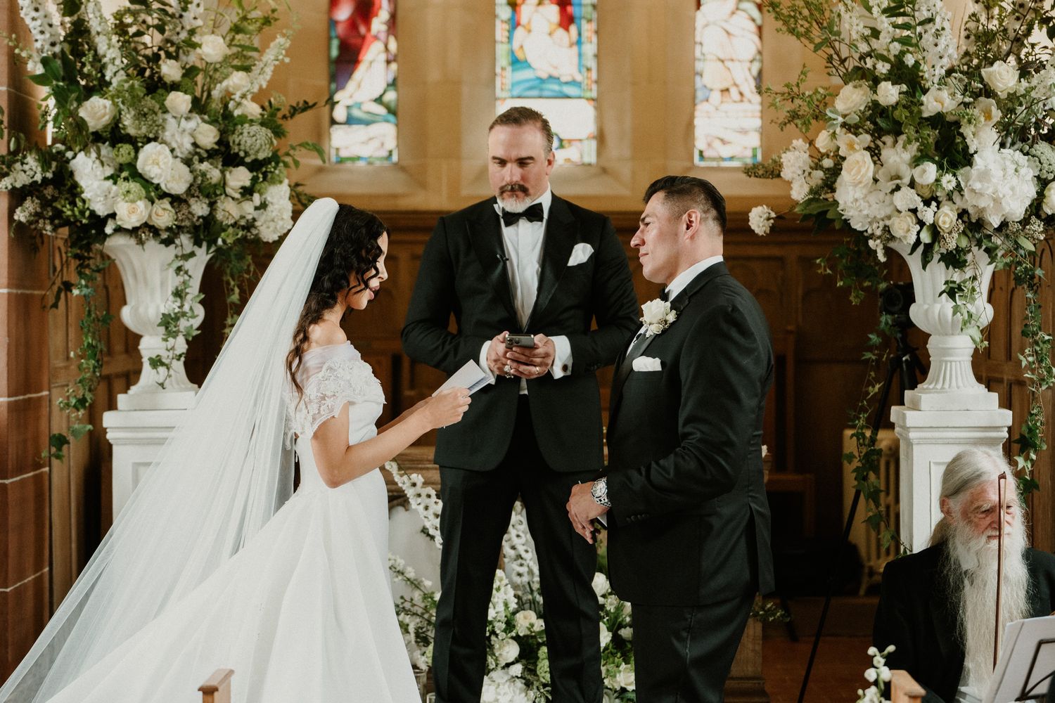 A wedding ceremony unfolds at the altar of a beautifully decorated church.