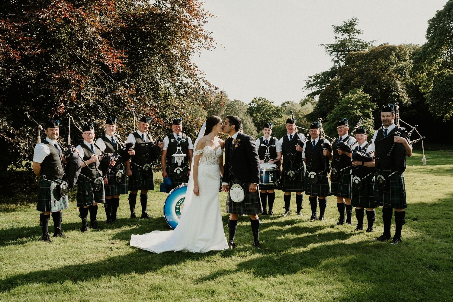 Wedding guests and musicians gather on castle lawn for Scottish celebration.