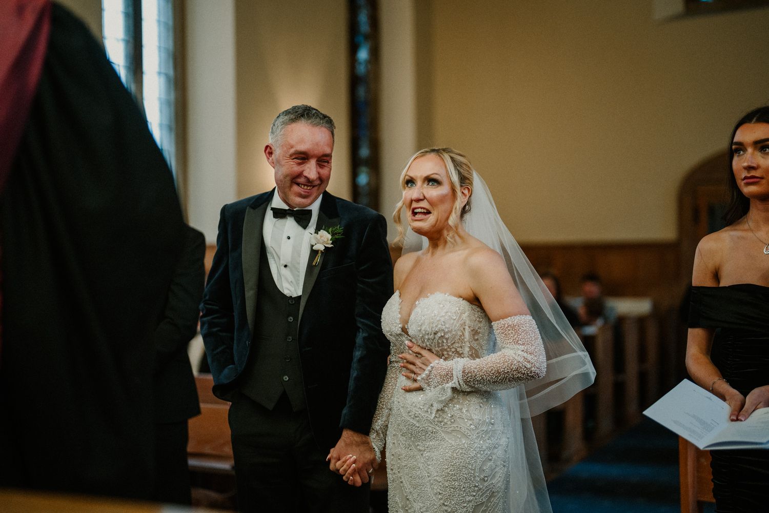 Emotional moment during church wedding ceremony with guests looking on.