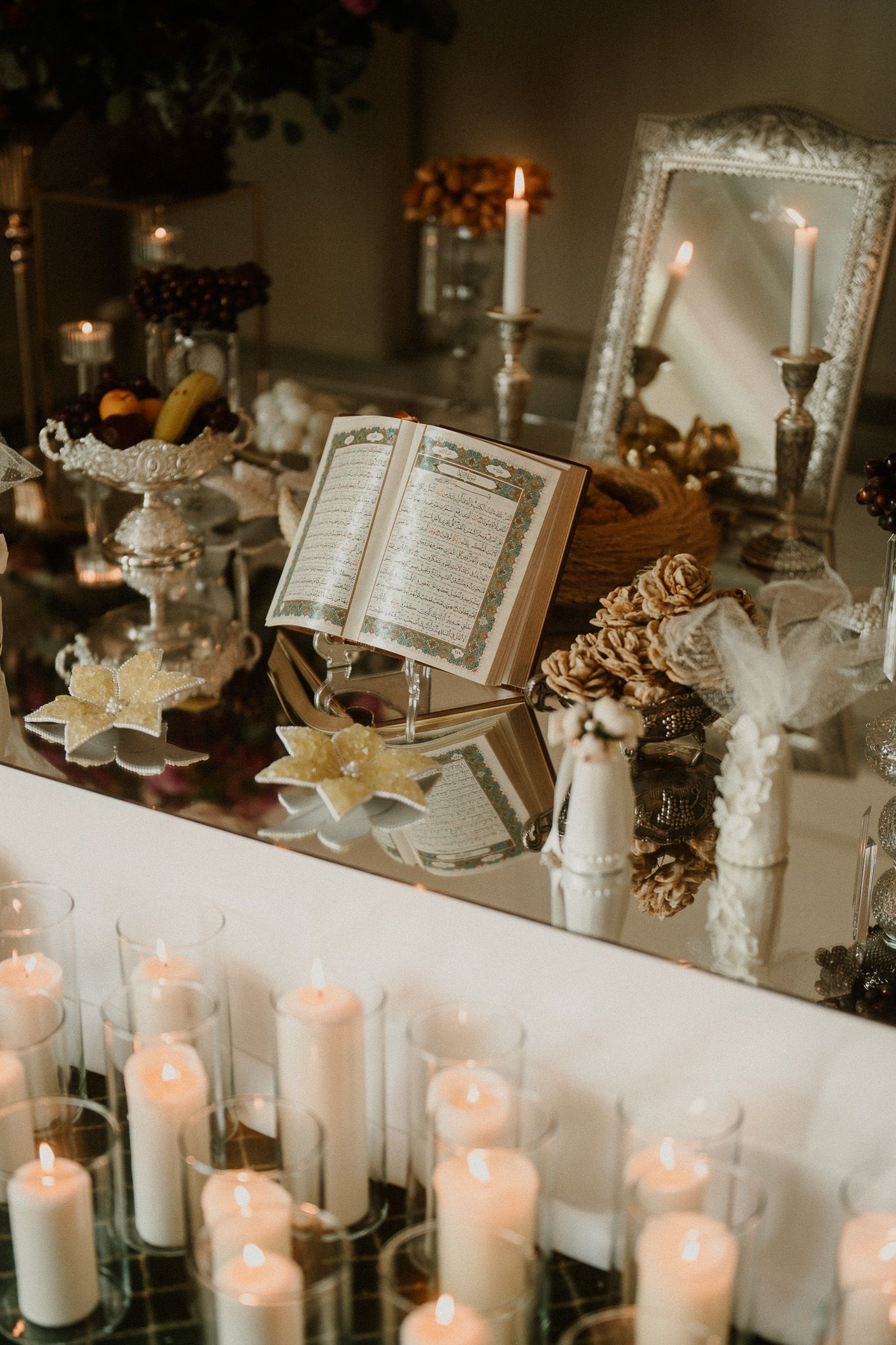 Elegant wedding reception table decorated with white candles and open books.