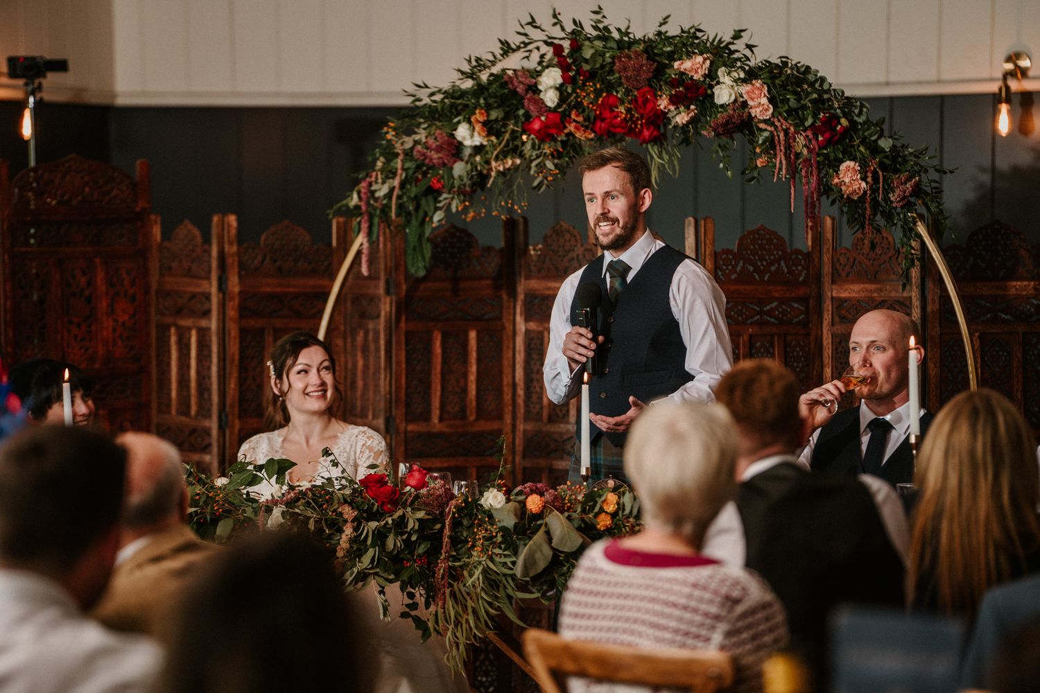 Wedding reception venue decorated with dramatic floral arrangements and mood lighting.