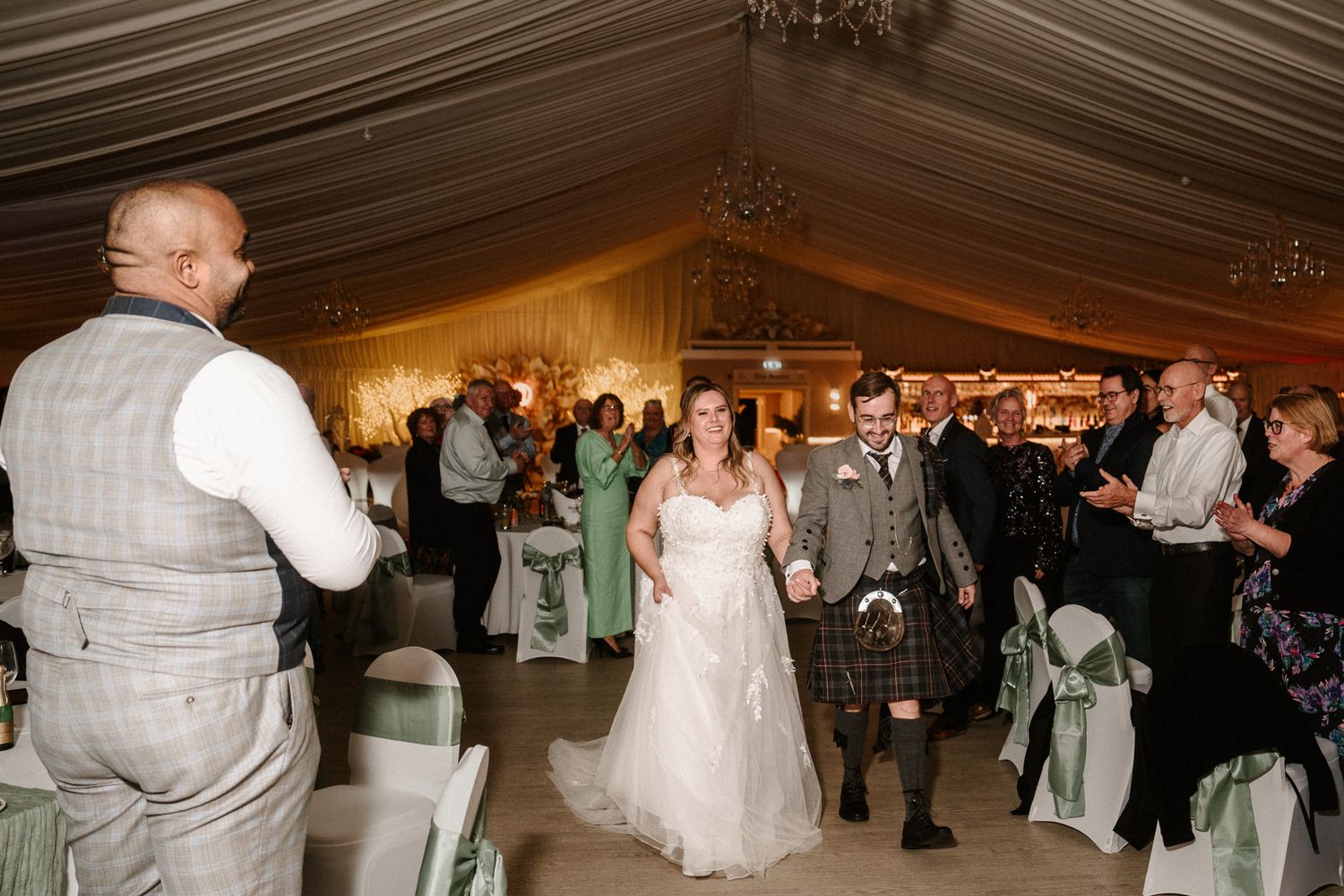 Wedding reception celebration in an elegant indoor venue with chandelier lighting.