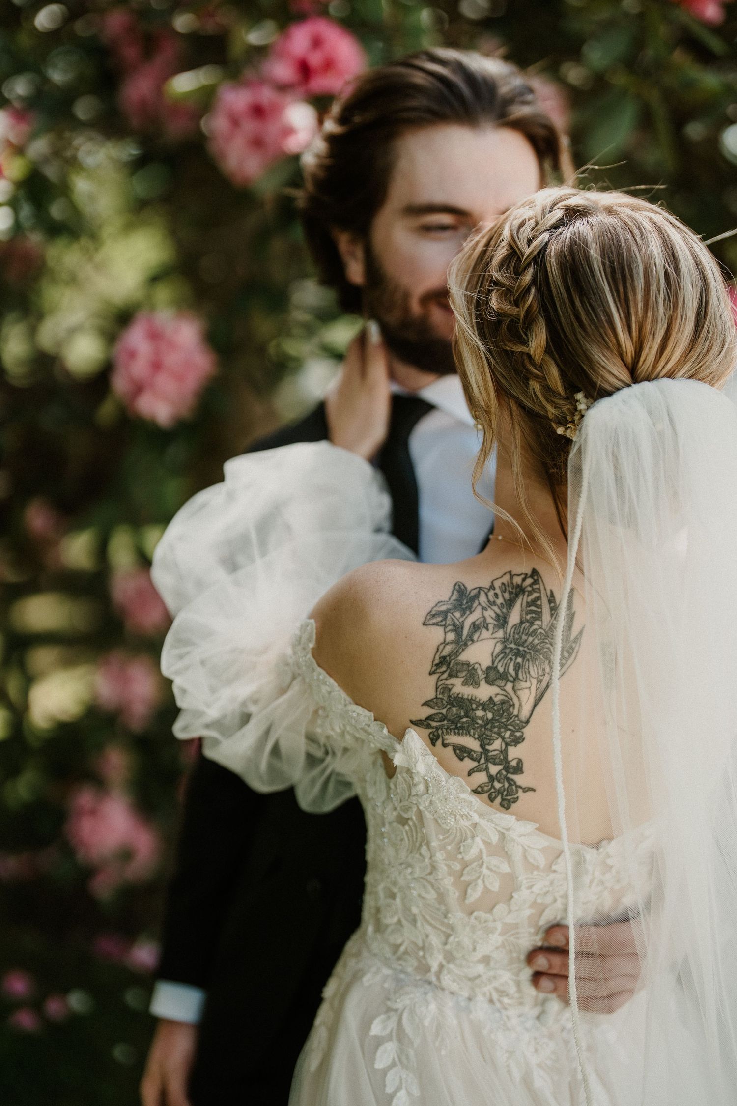 Back detail of wedding dress showing intricate lace pattern and flowing veil.