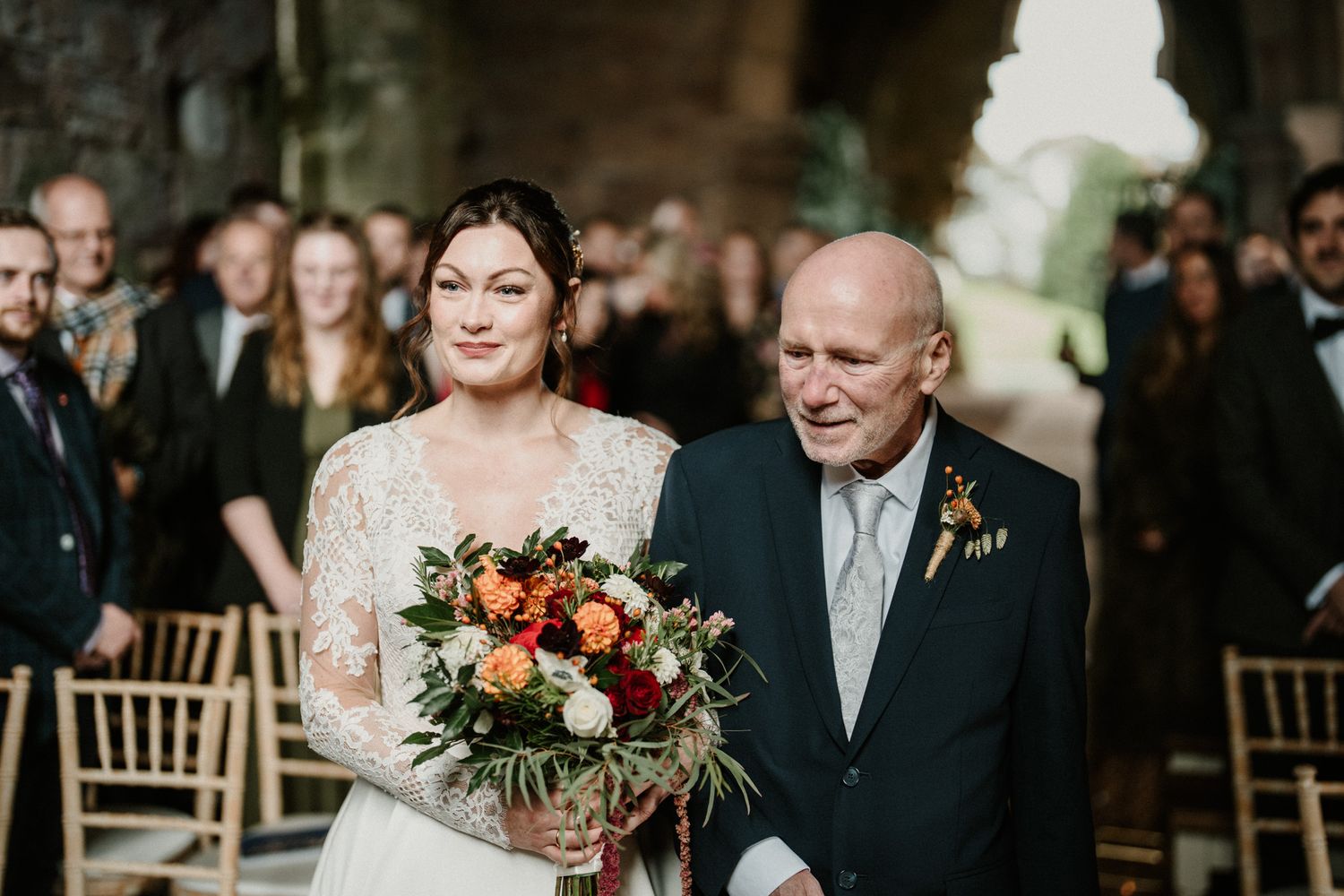 Wedding celebration in stone venue with floral arrangements and formal attire.