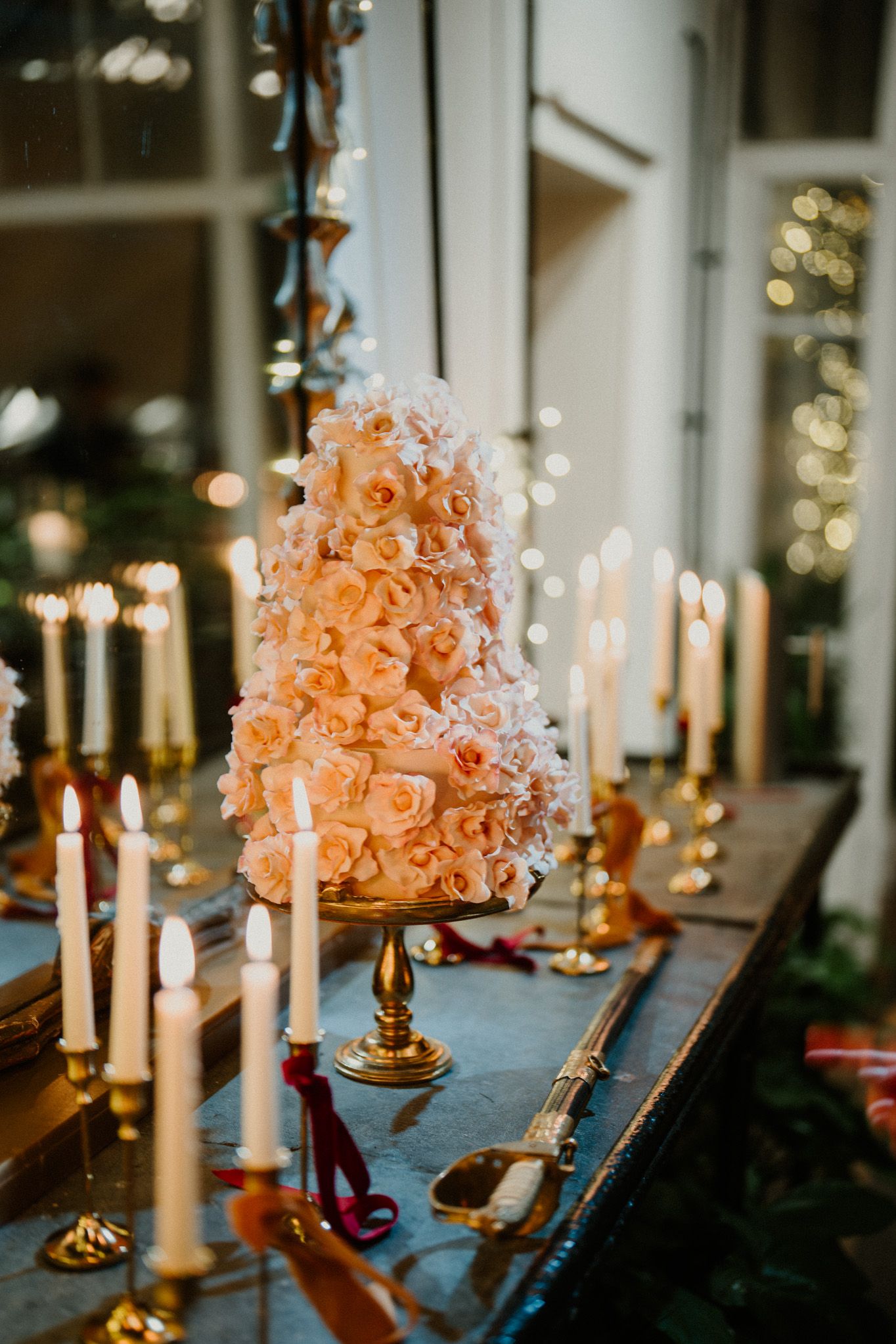Romantic dinner table with white tapered candles and peachy-pink floral centerpieces.