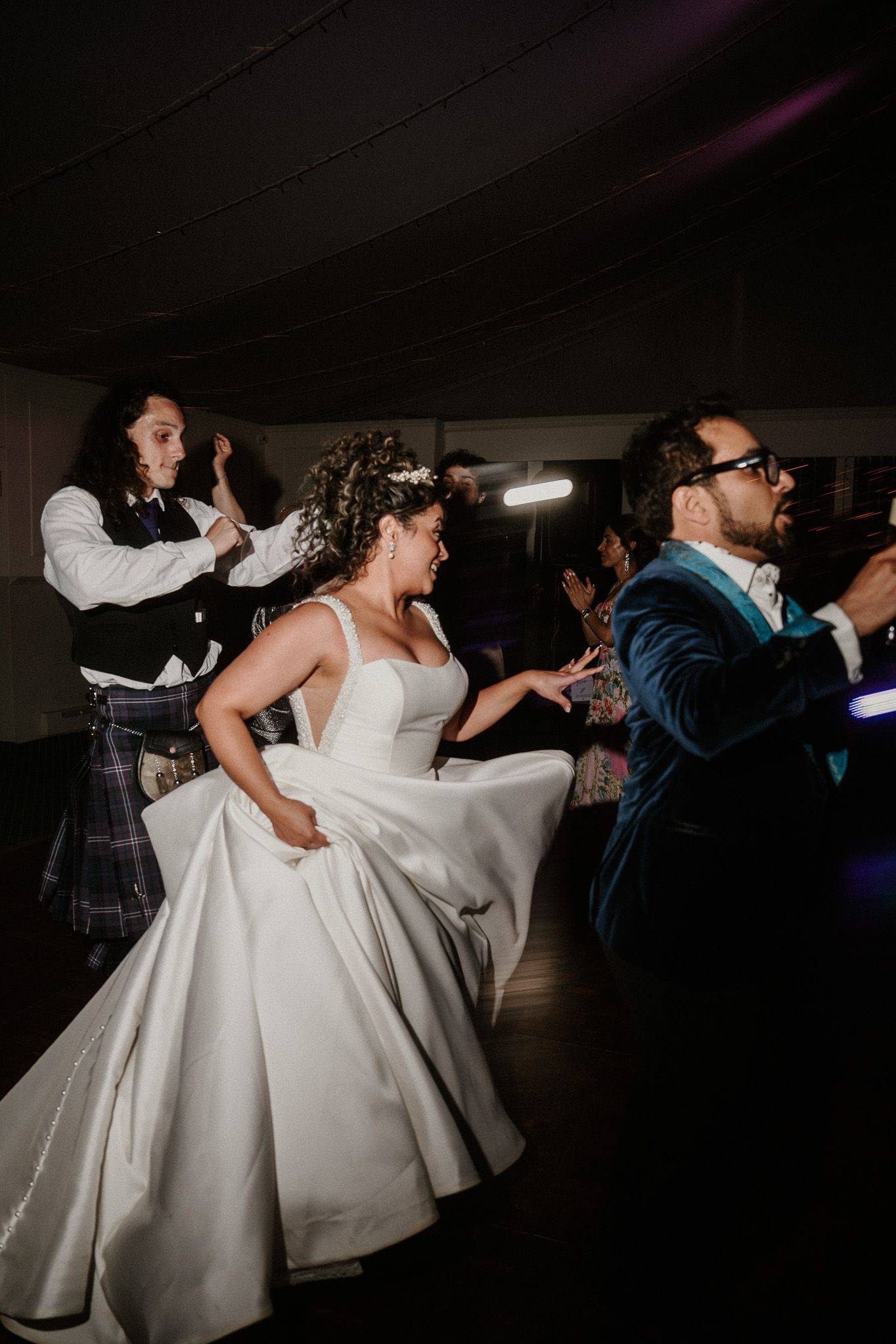 Wedding reception dance floor with guests and a bride in white dress moving to the music.