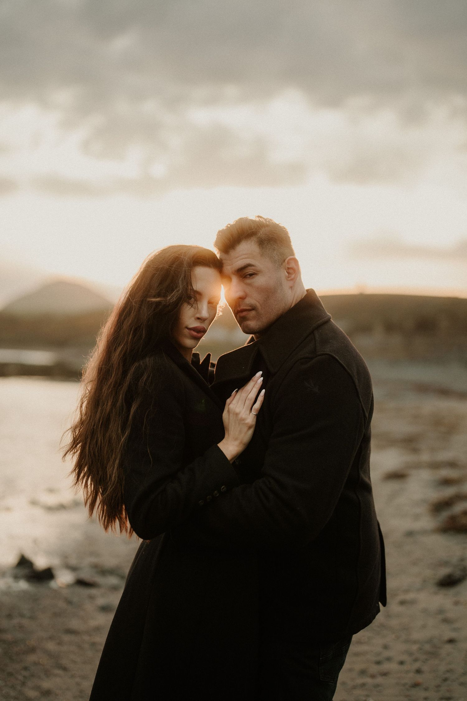 Intimate couple portrait at sunset against a moody coastal backdrop.
